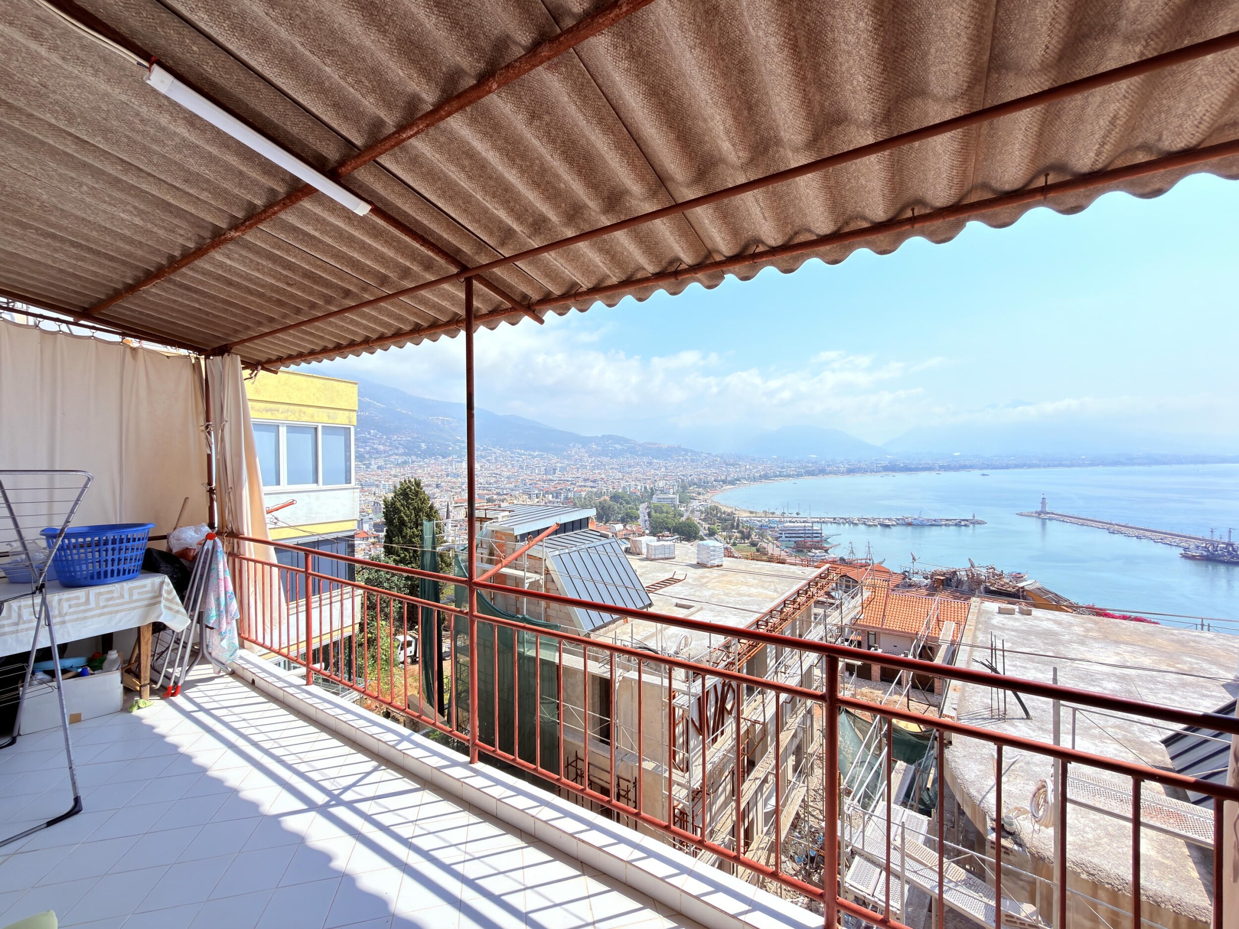 A spacious covered terrace with red railings and harbor view in Alanya, Turkey