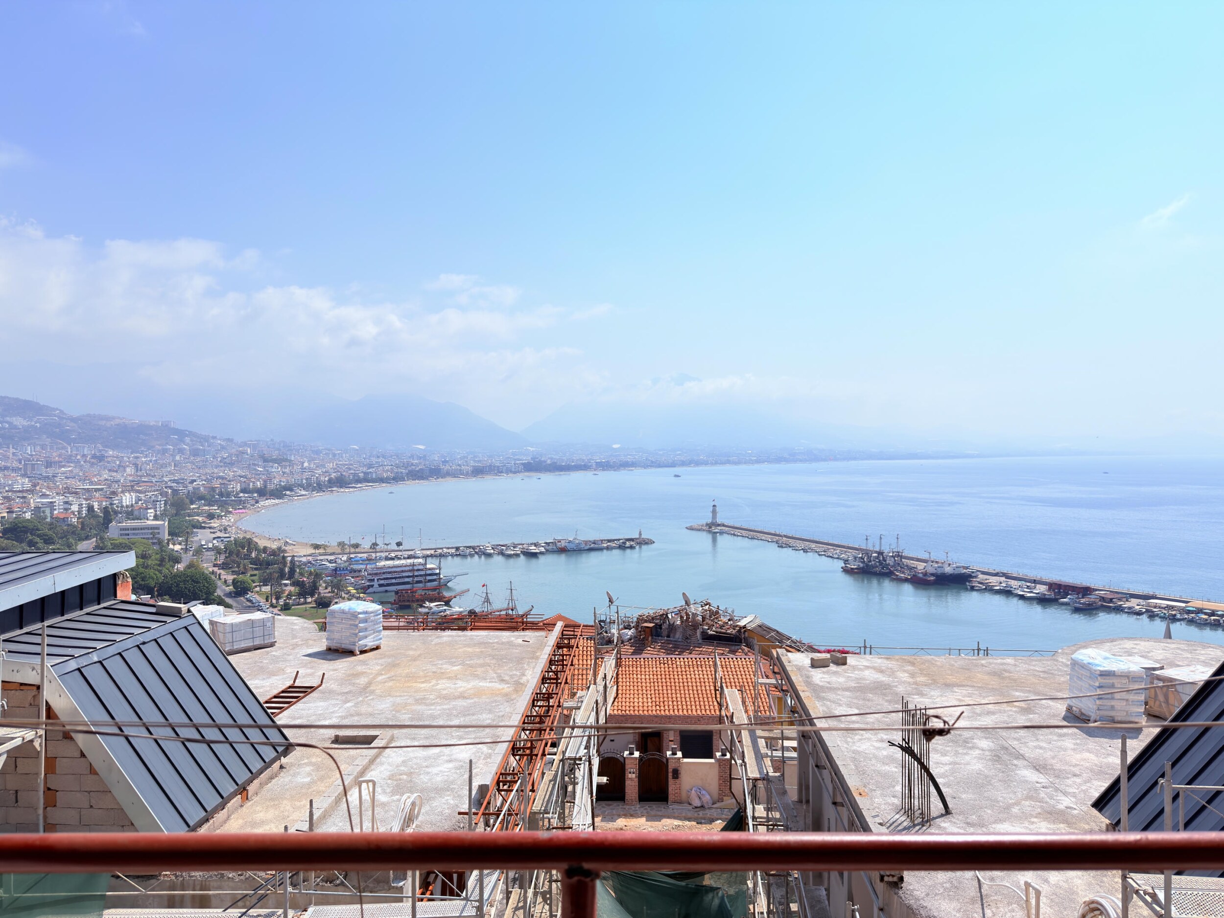 A terrace with red railings, breakwaters and calm sea is part of a villa in Turkey for sale