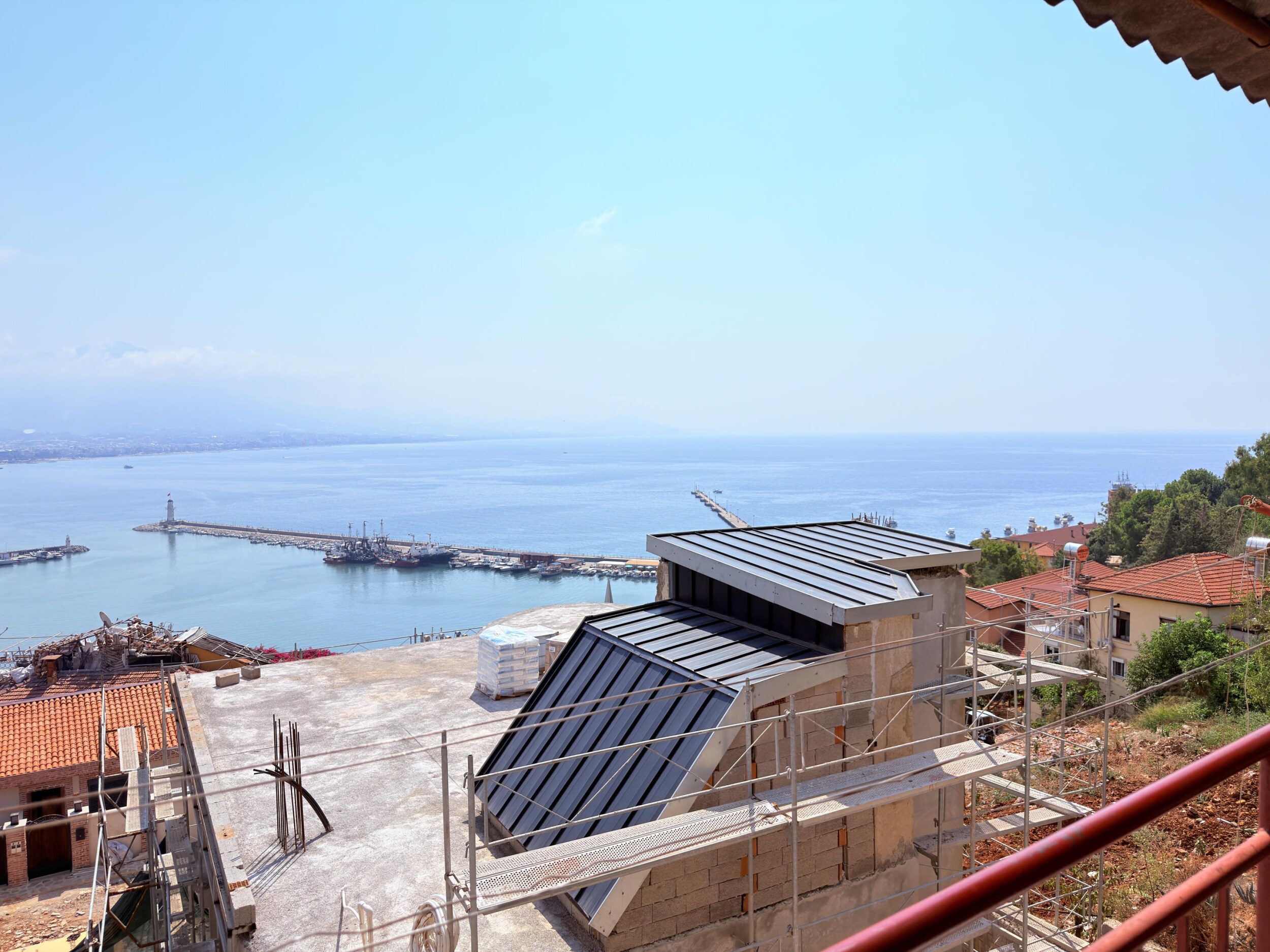 A villa terrace with sea view, lighthouse breakwater and green hillside in Alanya