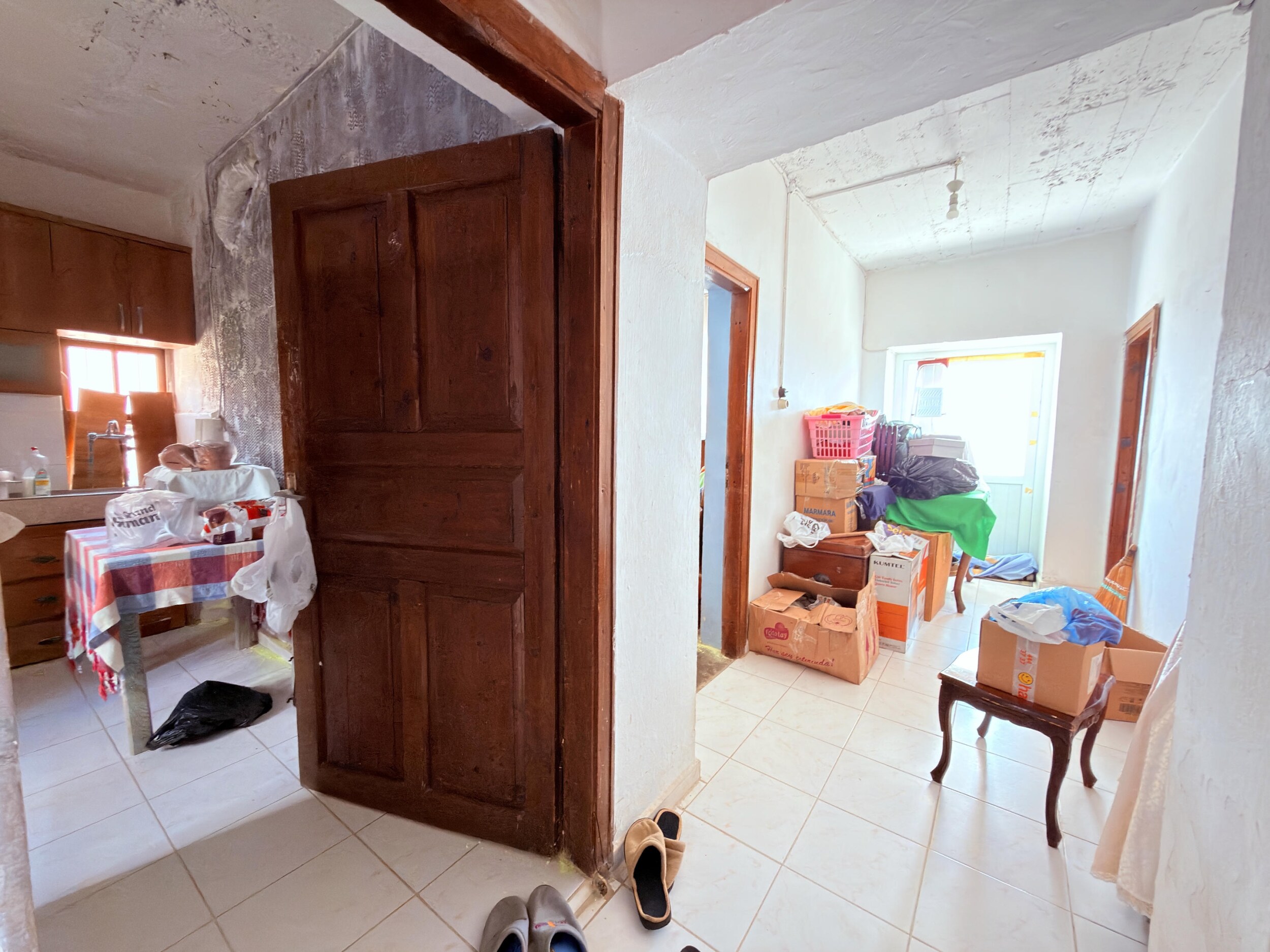 A bright tiled corridor with doors, boxes and a kitchen area in a villa