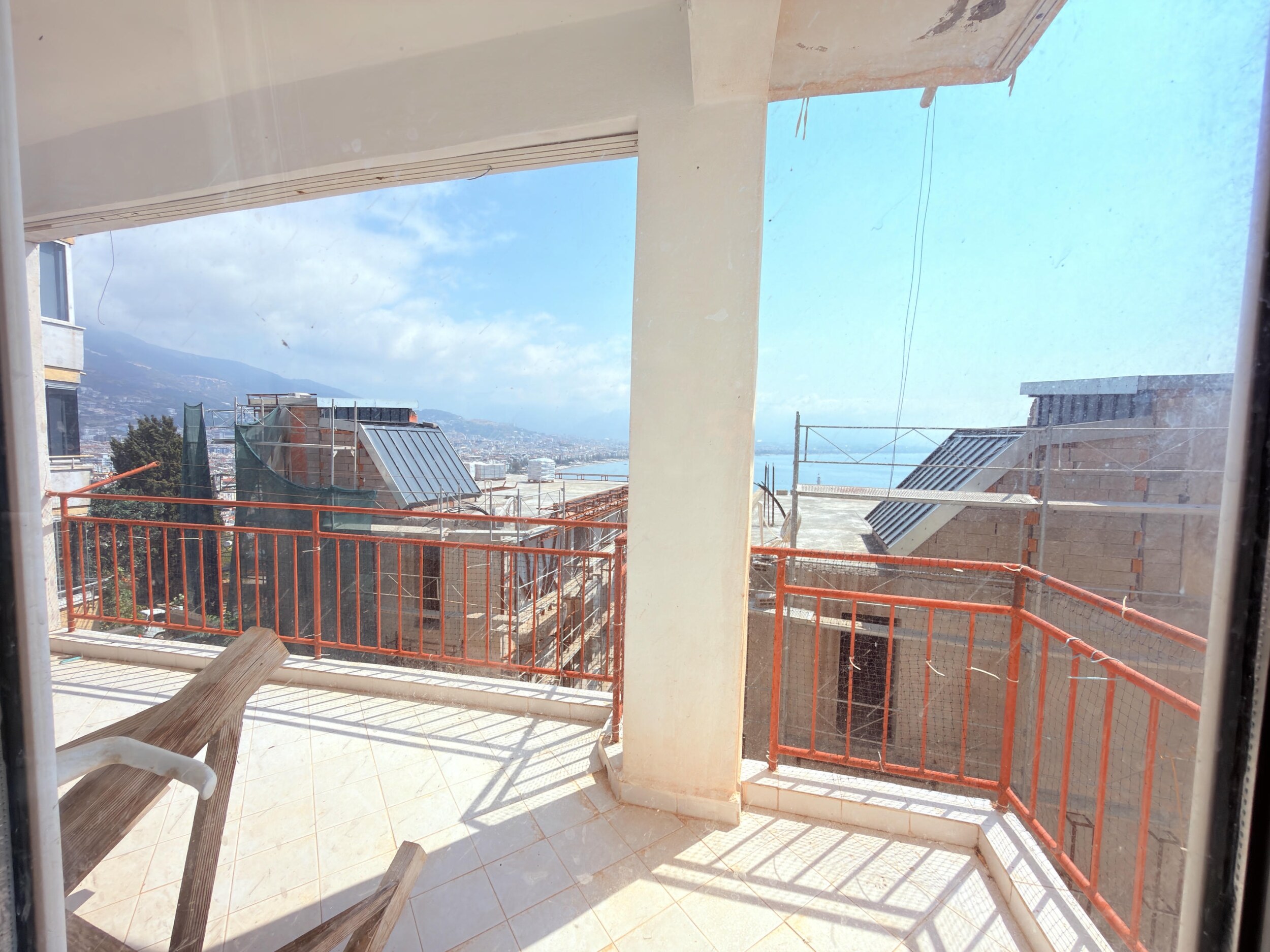 A spacious terrace with red railings and distant bay view in Alanya where a home is for sale