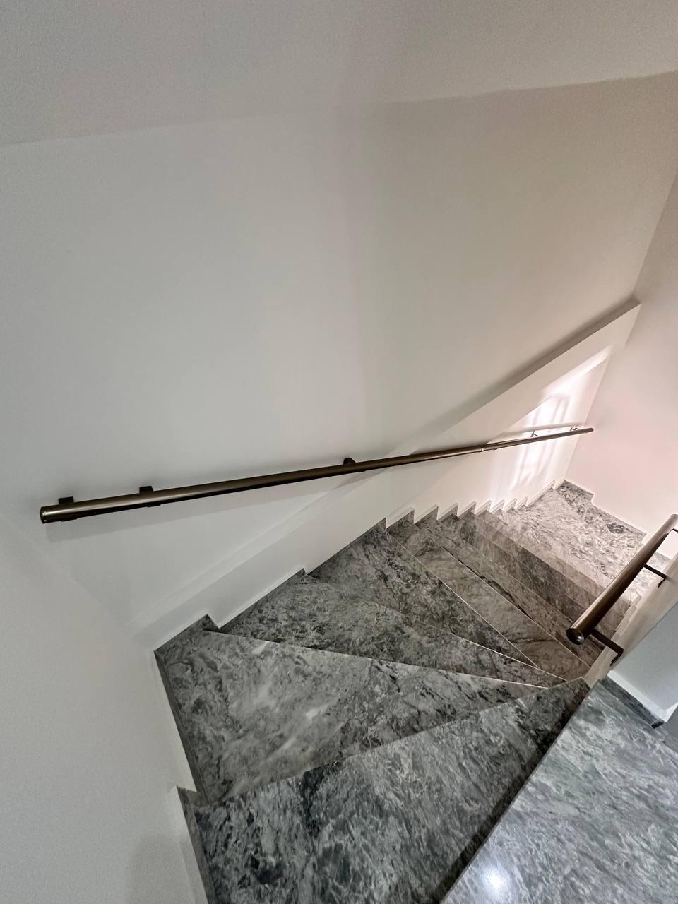 Spiral merdiven, mermer basamaklar ve metal korkuluklarla pencere ışığı alan dar geçitte yükseliyor