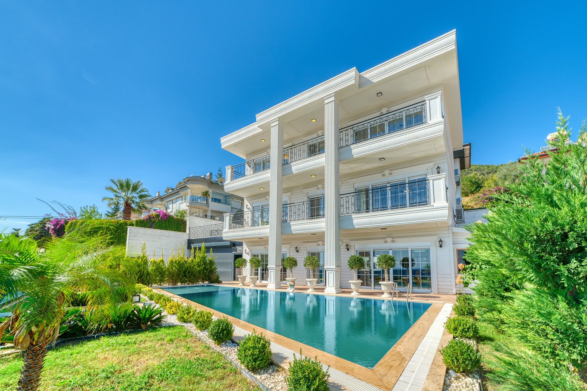 White villa facade with a pool along the building and panoramic first-floor glazing in Alanya, Turkey