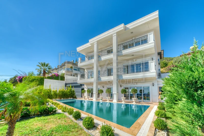 White villa facade with a pool along the building and panoramic first-floor glazing in Alanya, Turkey
