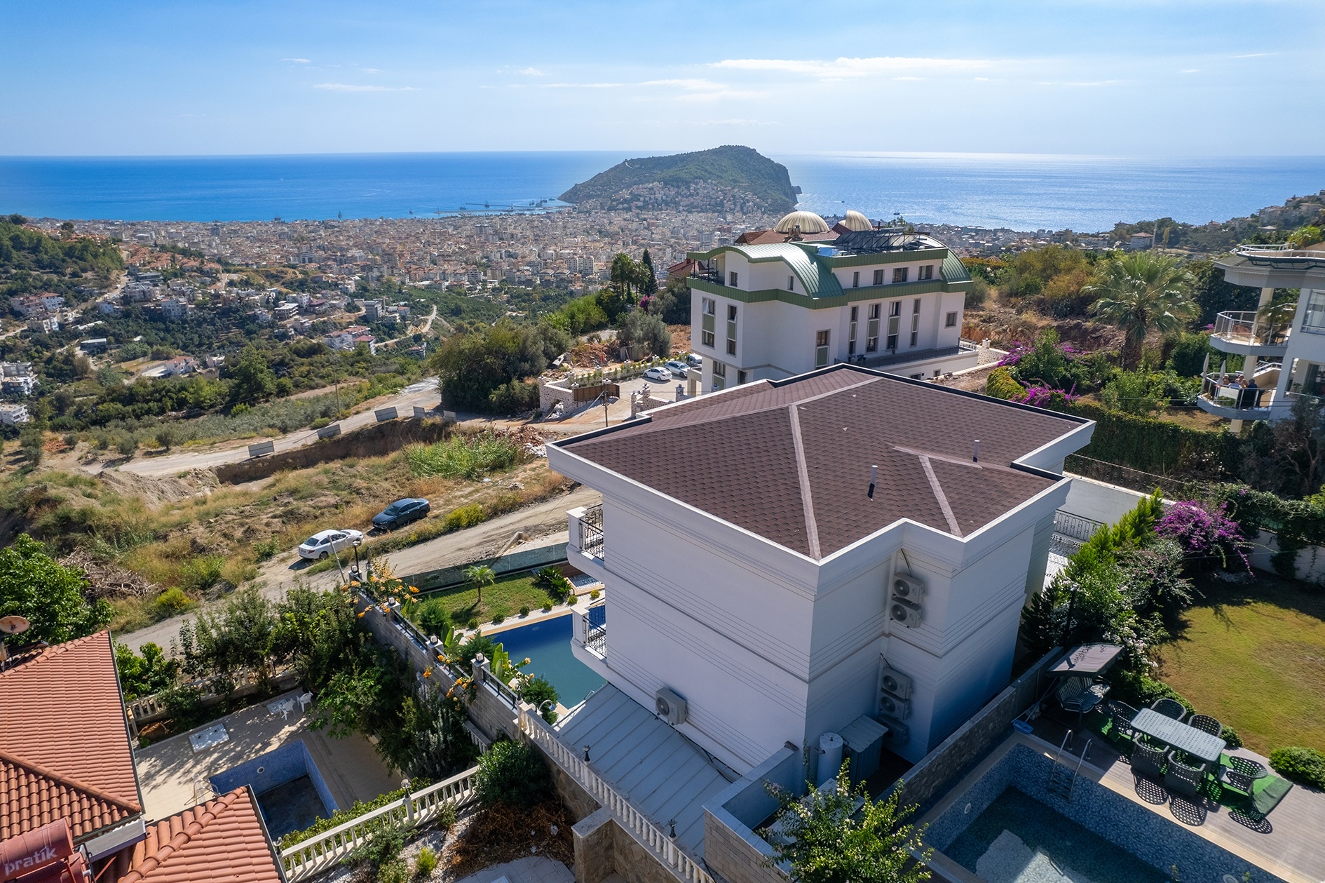 Panoramic coastal view with a rocky headland and a villa roof in the foreground in Alanya, Turkey