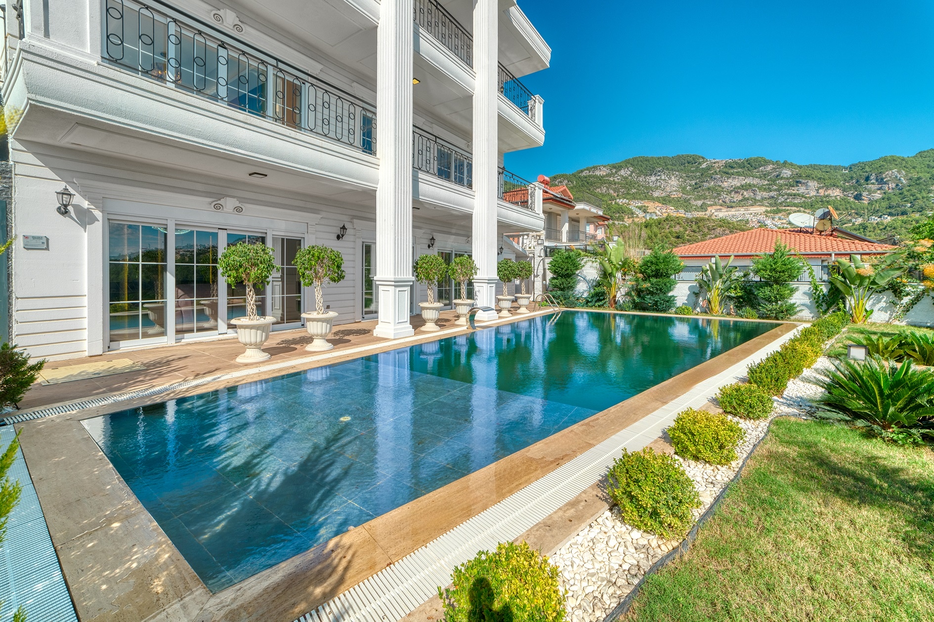 Open pool before a white villa facade with columns and balconies in Alanya, Turkey