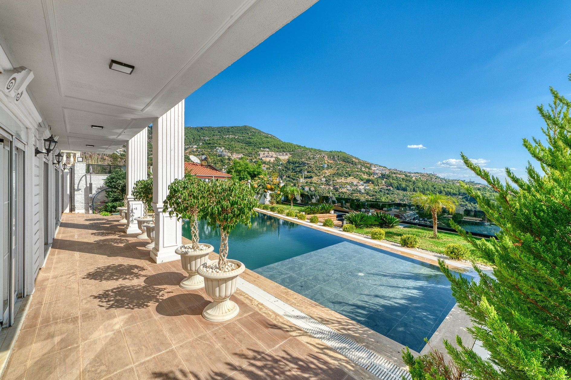 Pool beside a covered villa terrace with columns and a mountain view in Turkey for sale