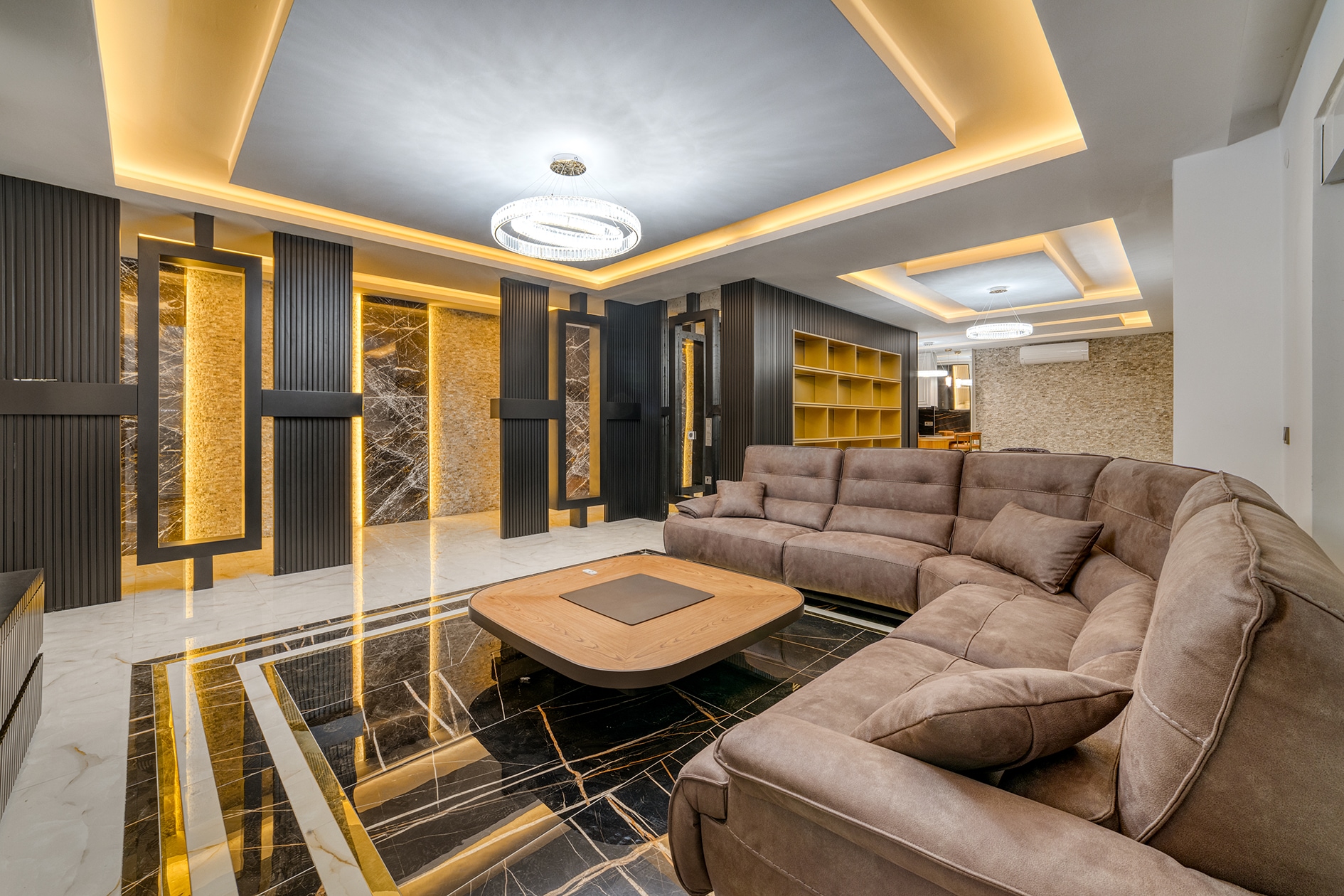 House living room with a brown sofa, black-and-gold rug and illuminated wall panels in Alanya