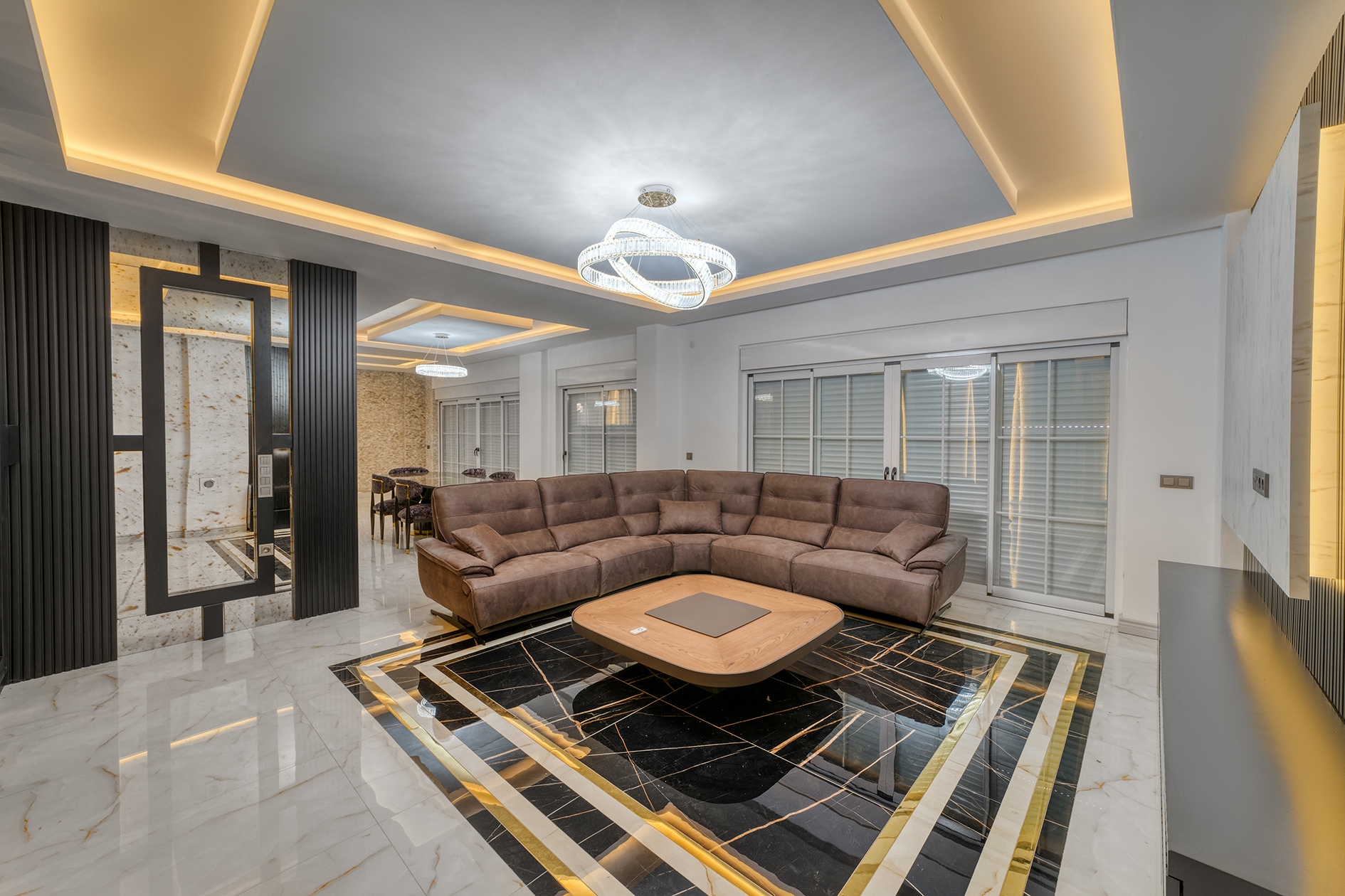 Living room with a long brown sofa, panoramic windows and glossy marble flooring in Turkey