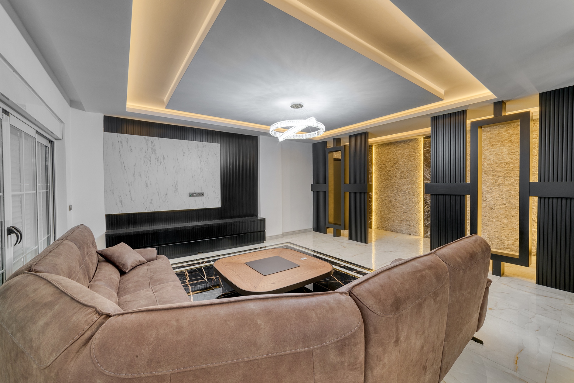 Brown corner sofa and oval table in a villa living room with a marble wall panel in Turkey for sale