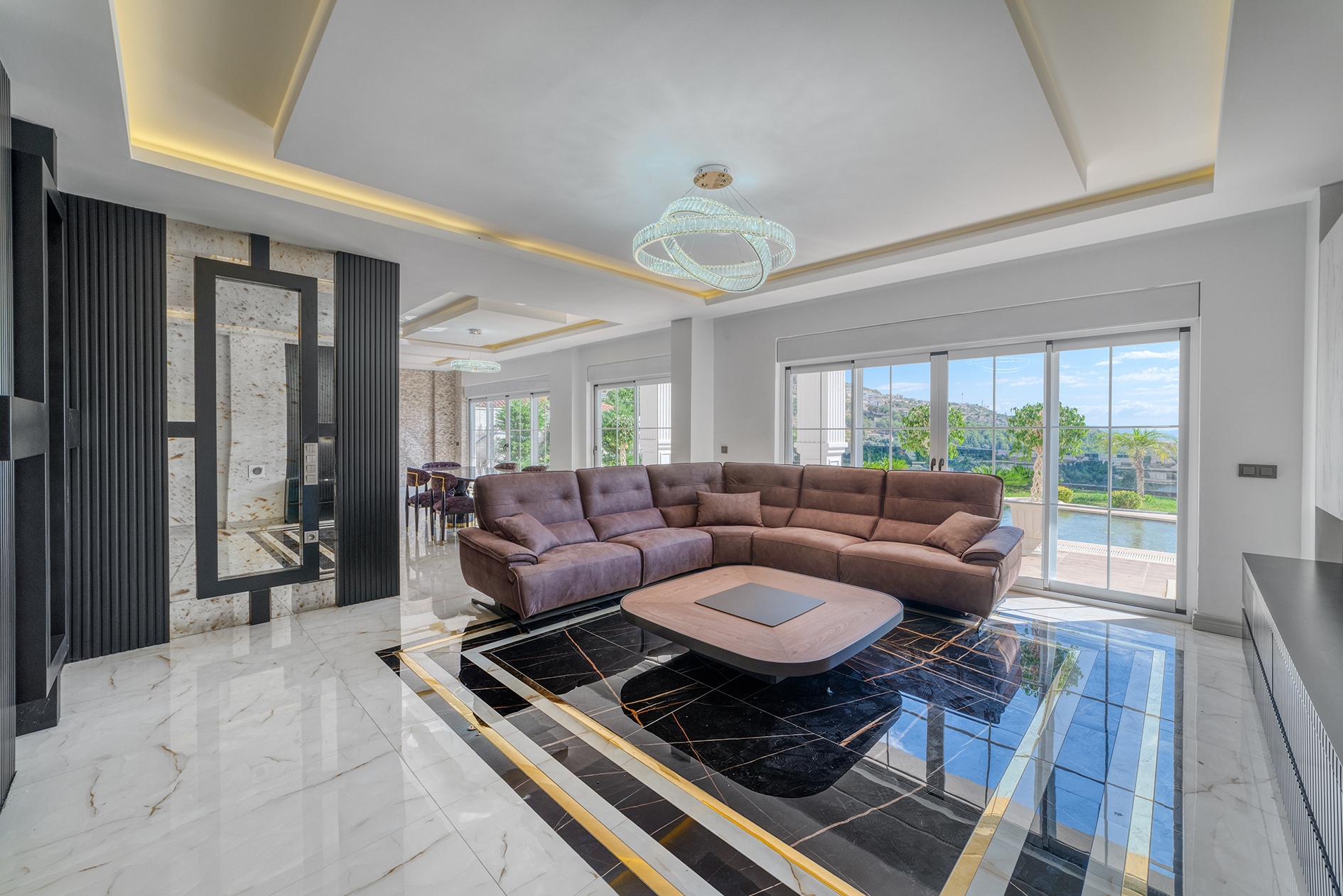 Villa living room with a brown sofa, sliding doors, pool and mountain view in Turkey