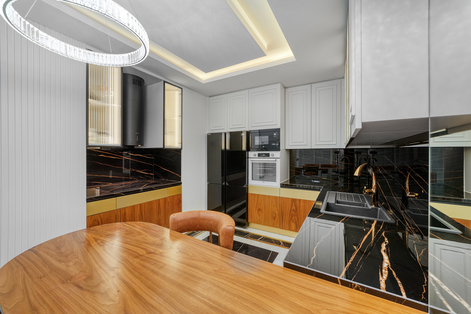 Kitchen with a black veined countertop, white cabinets and round wooden table in Alanya