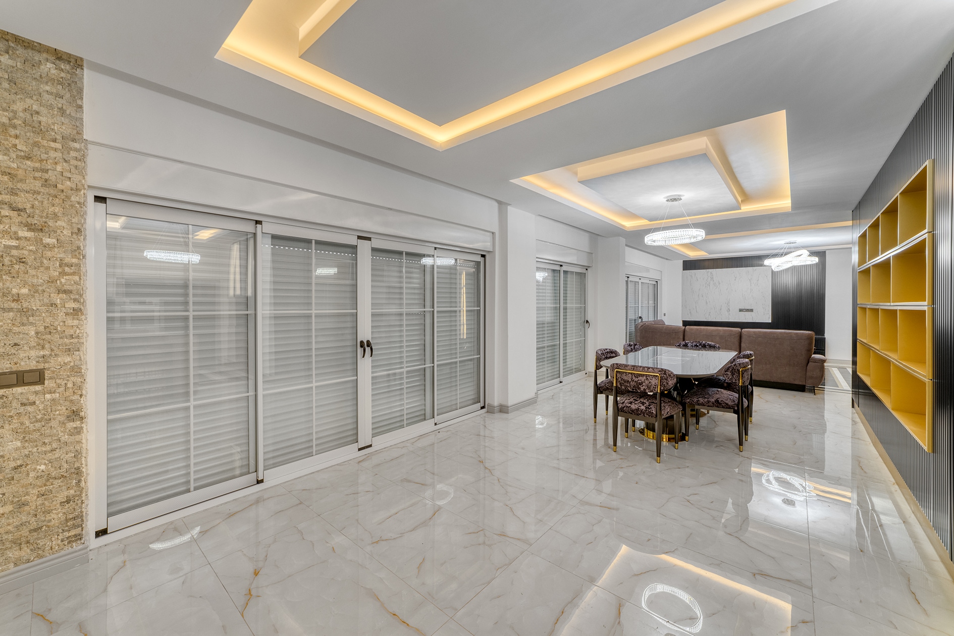 Living room with a brown sofa, dining area and wide sliding windows for sale