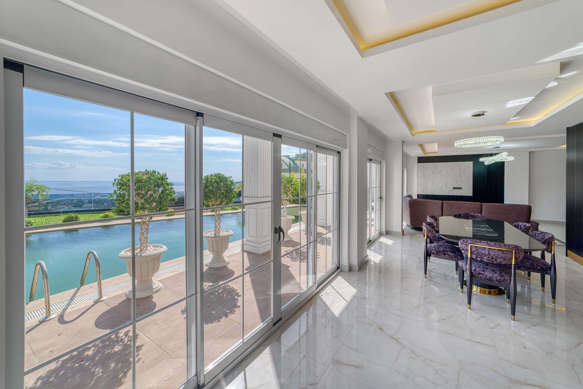Villa dining area with a glass table, six chairs and pool beyond the windows for sale
