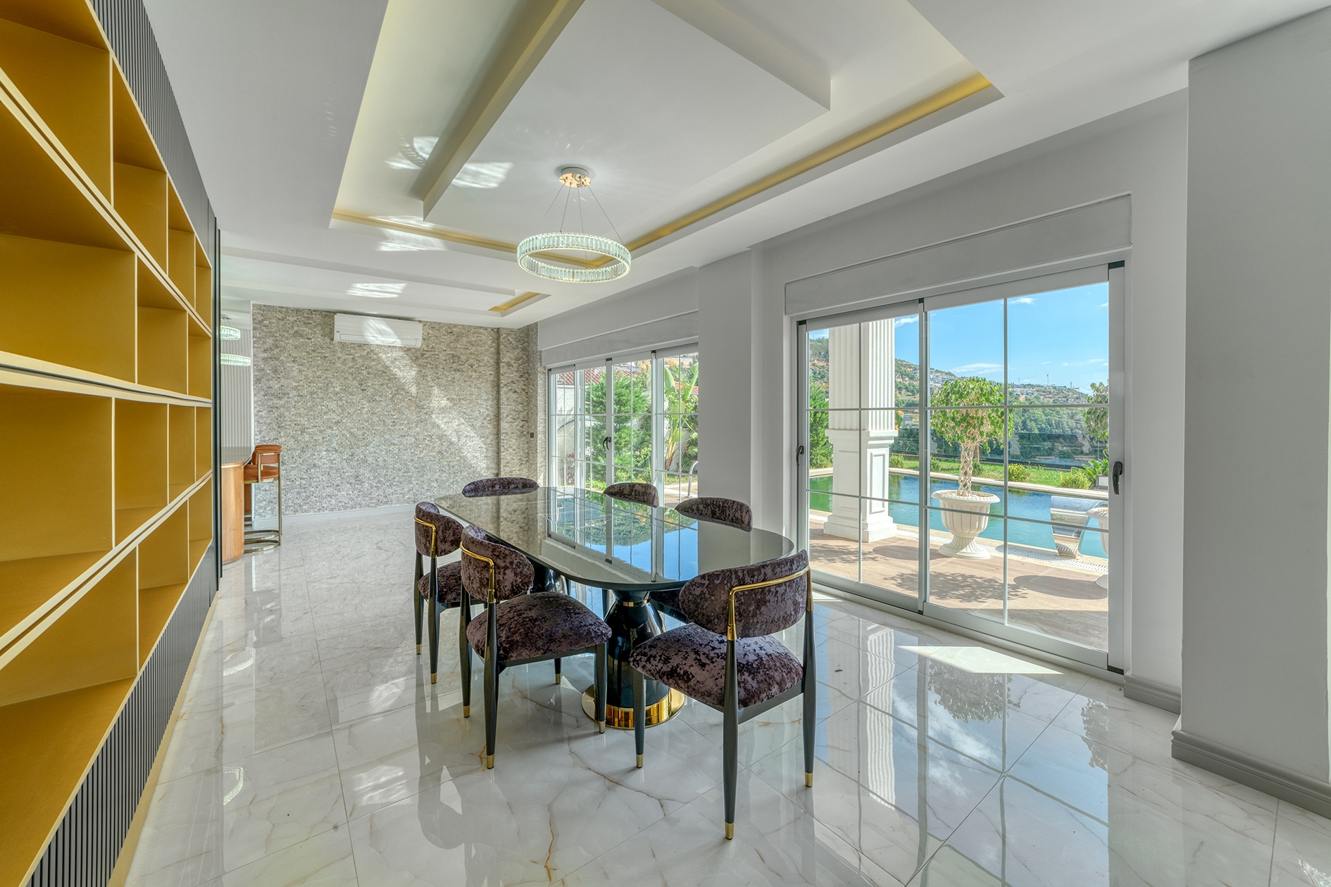 Dining area with panoramic windows, yellow shelving and a pool on the terrace in Alanya, Turkey