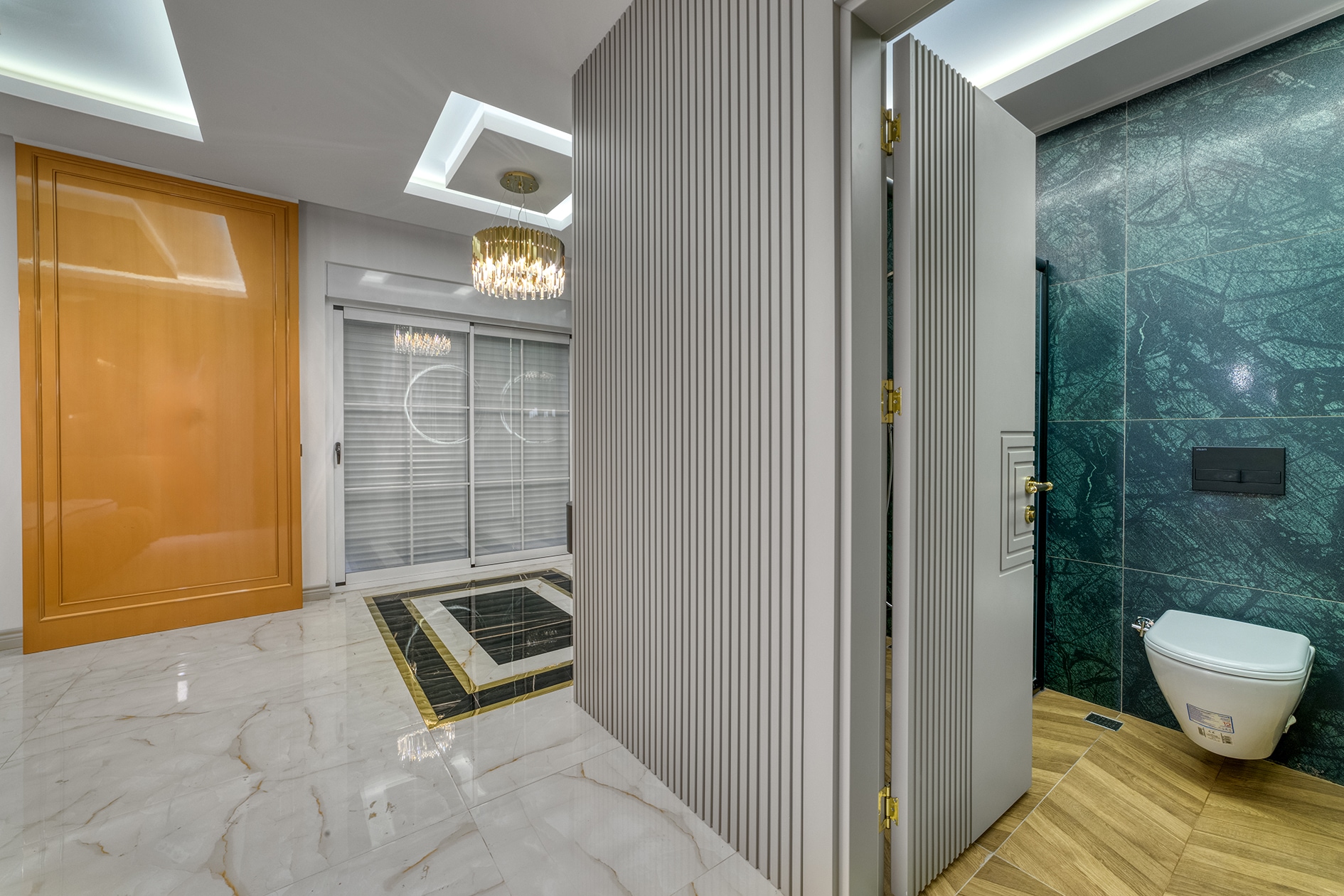 Wide villa hall with marble flooring, wooden entrance door and crystal chandelier