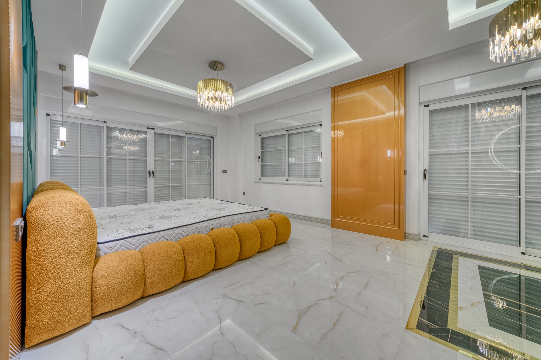 Villa bedroom with an orange bed, several windows and glossy marble flooring in Alanya