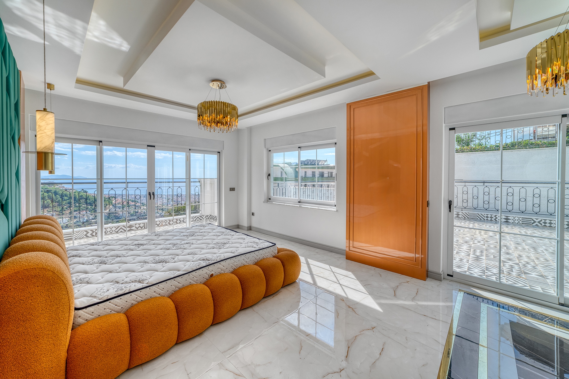 Villa bedroom with an orange bed, terrace doors and mountain landscape in Turkey