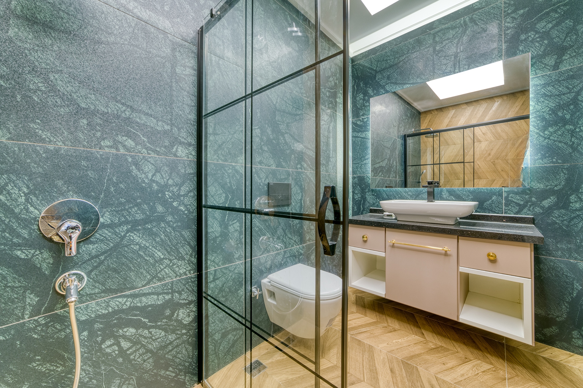 Villa bathroom with green marble walls, framed shower screen and white basin