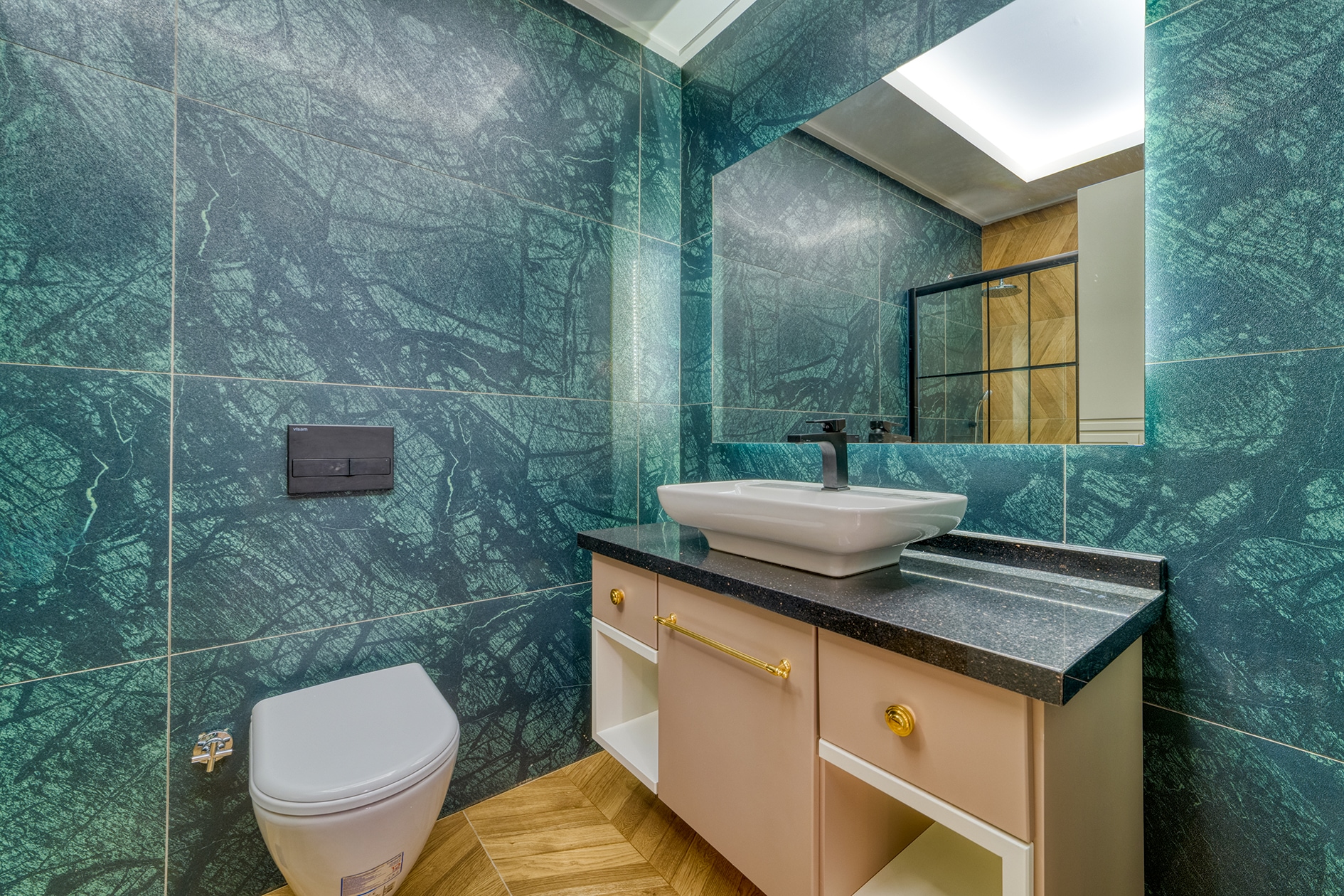 Bathroom with green marble walls, white basin and beige vanity in Alanya