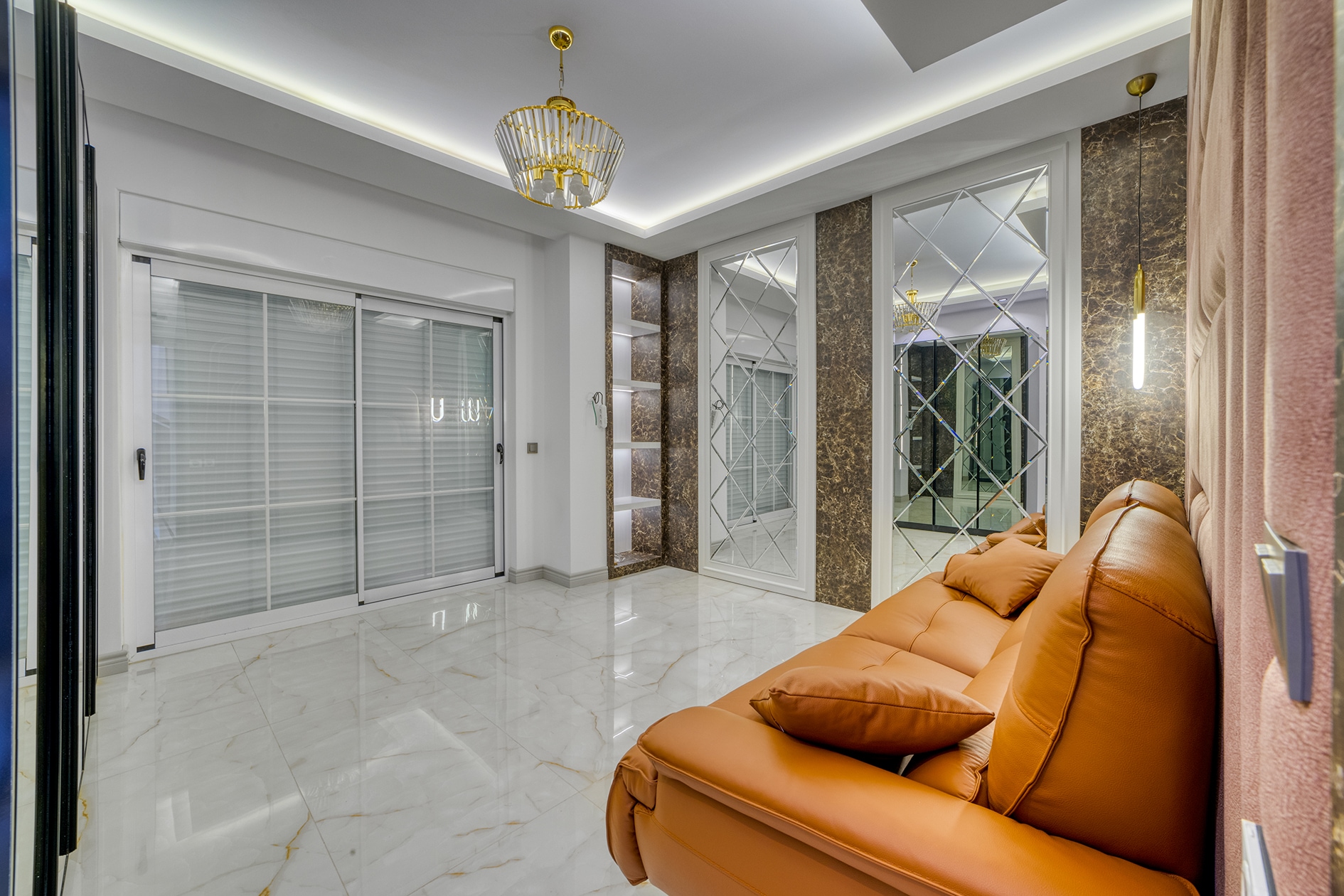 Orange sofa by panoramic sliding windows and built-in shelves in a villa for sale in Alanya