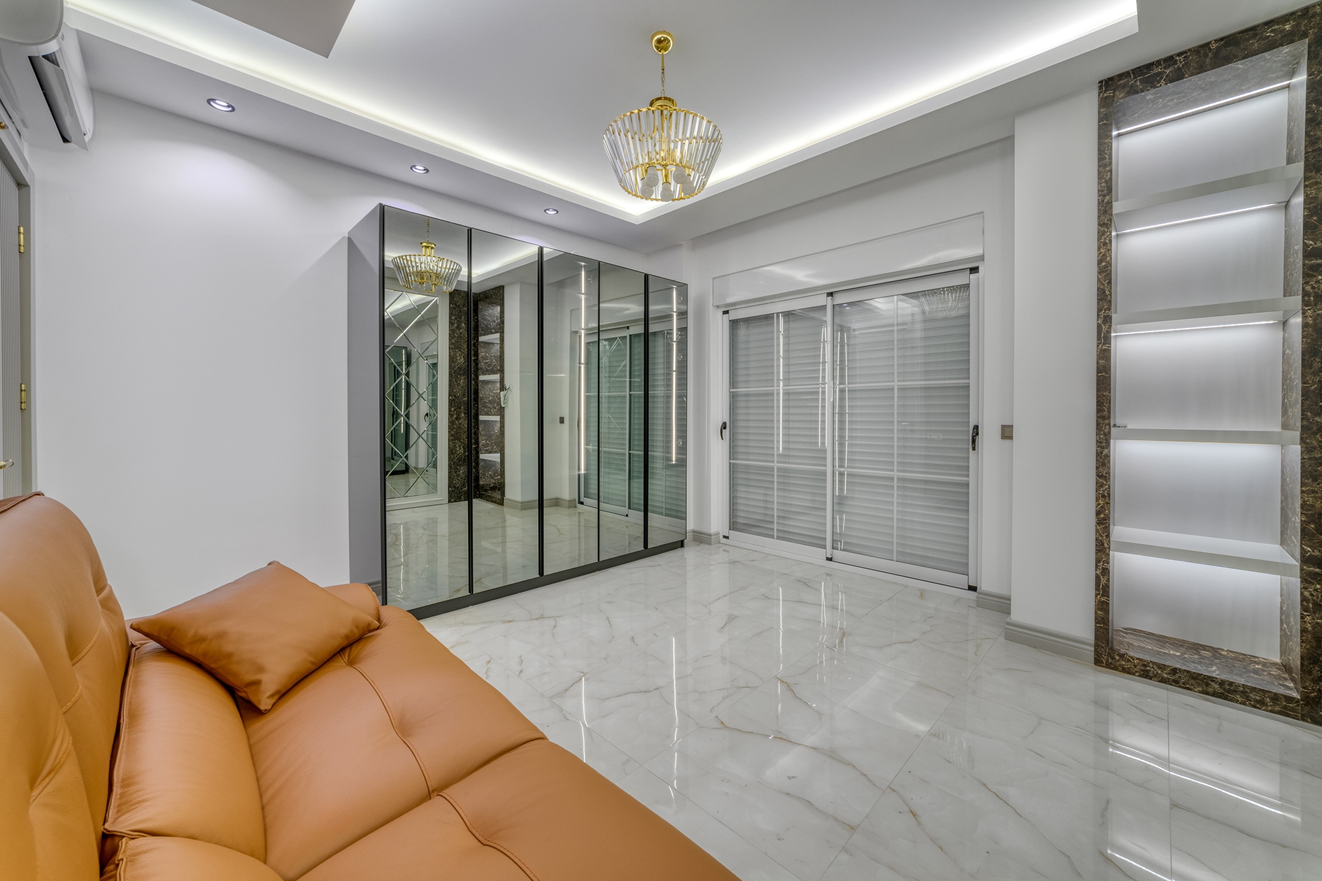 Orange corner sofa beside a mirrored wardrobe and marble floor in a villa for sale in Turkey
