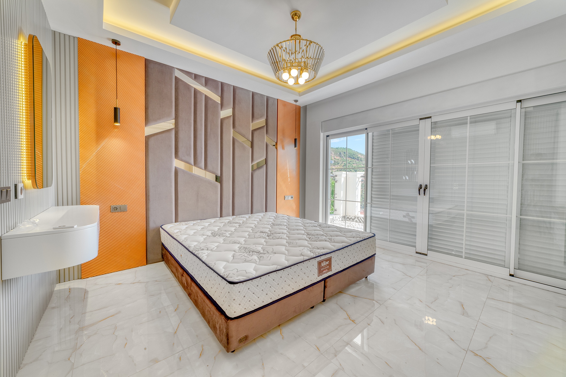Double bed beside an orange and beige accent wall with panoramic glazing in a villa