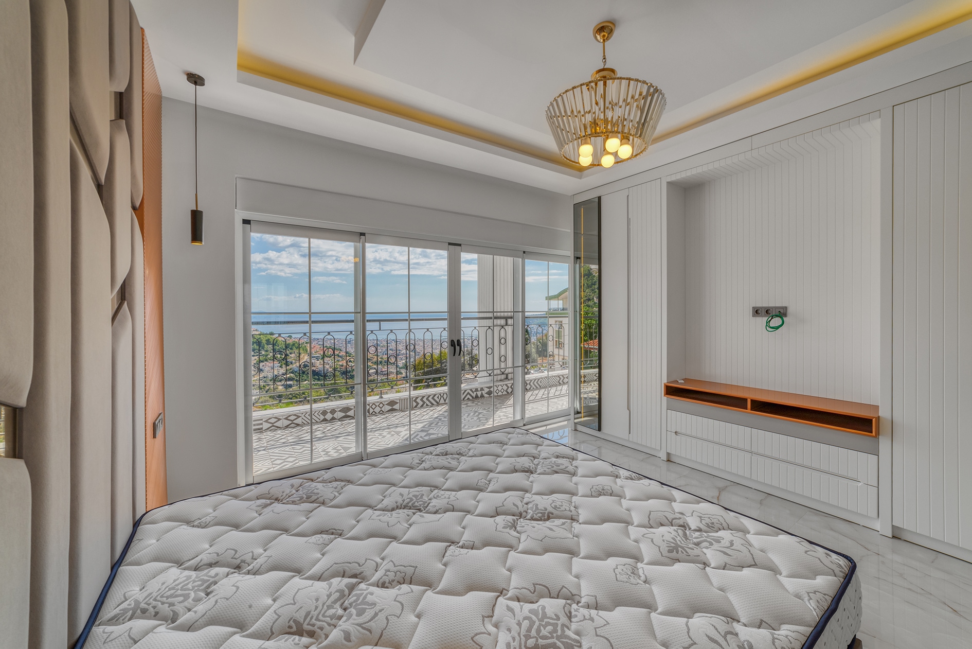 Double bed and panoramic balcony doors overlooking the sea and city in a villa in Alanya