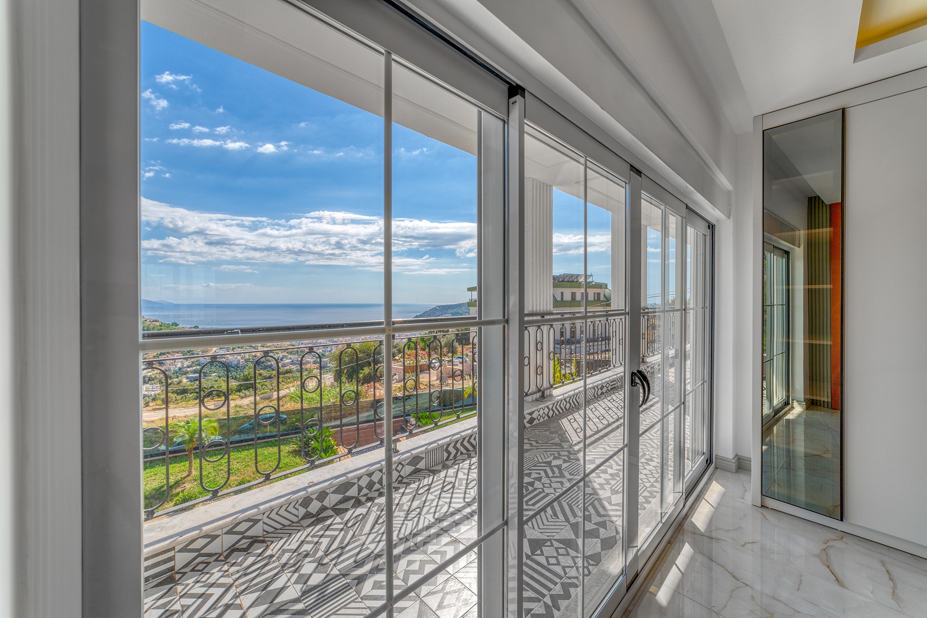 Glazed terrace with black-and-white tiles and sea views beside a 5+1 villa in Turkey