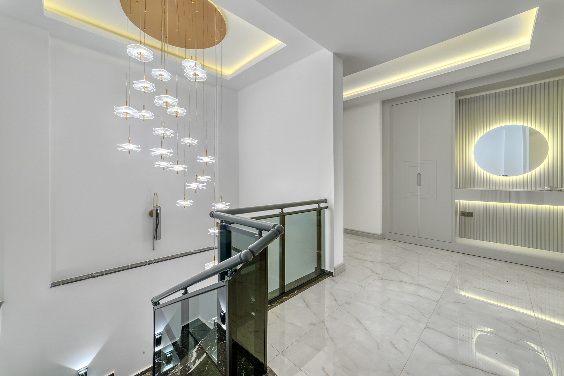 Hall by the staircase with a round mirror and pendant lights in a house in Alanya