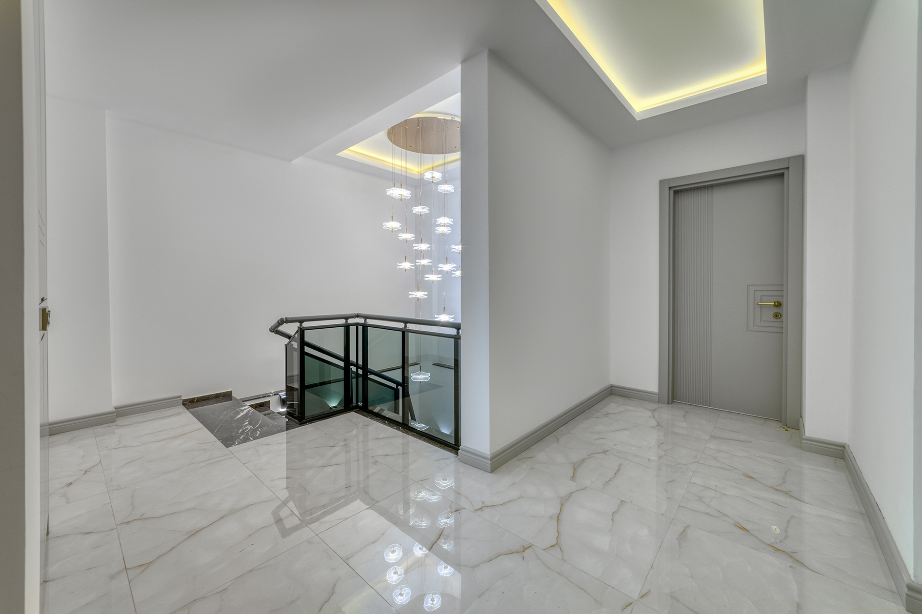 Glass stair railing and veined white marble floor in a villa hall in Alanya