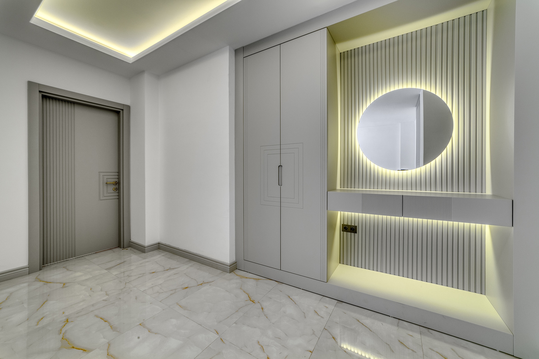Gray entrance door and round illuminated mirror in a house hall in Alanya