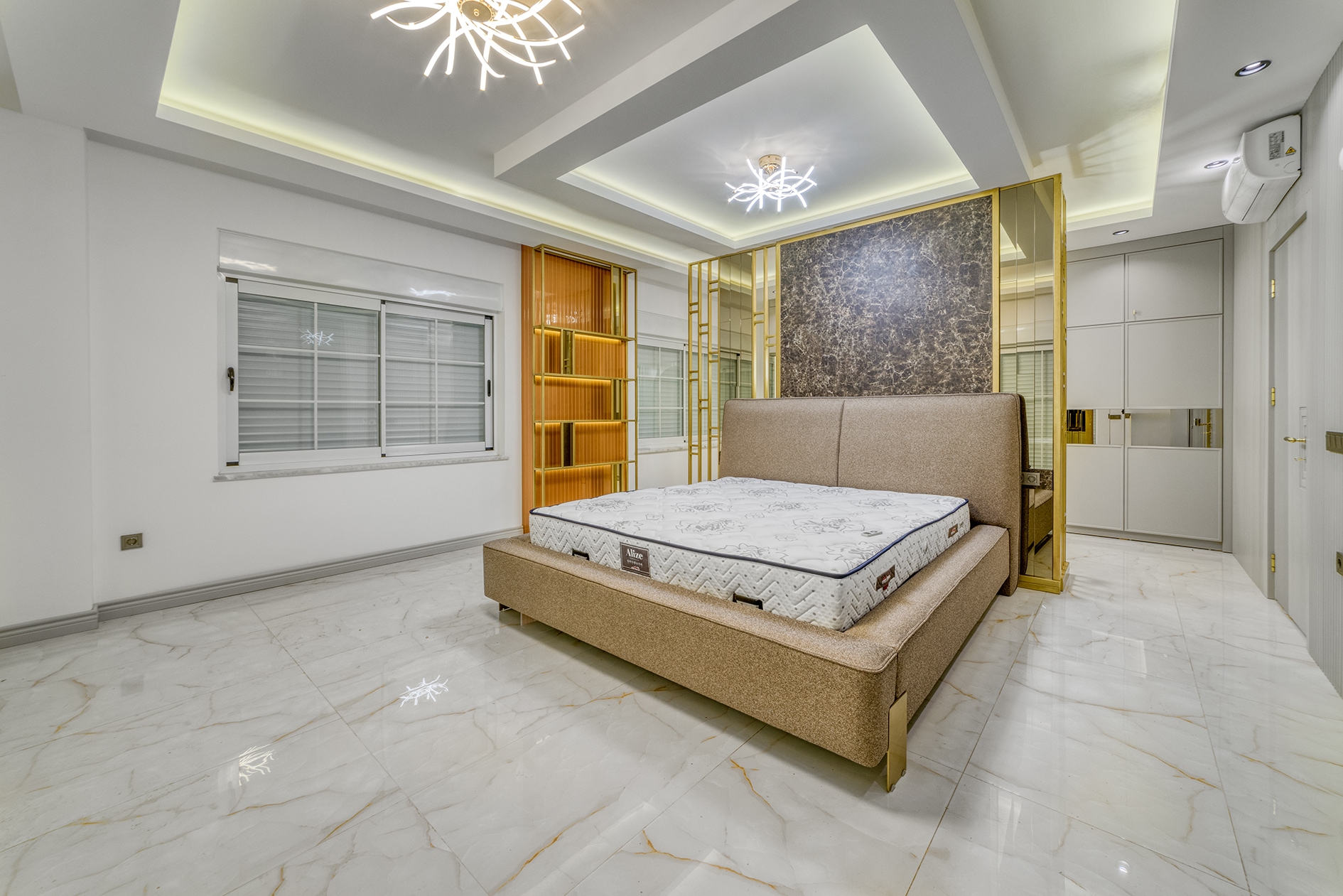 Beige bed with floral mattress and gold shelving in a house bedroom in Alanya
