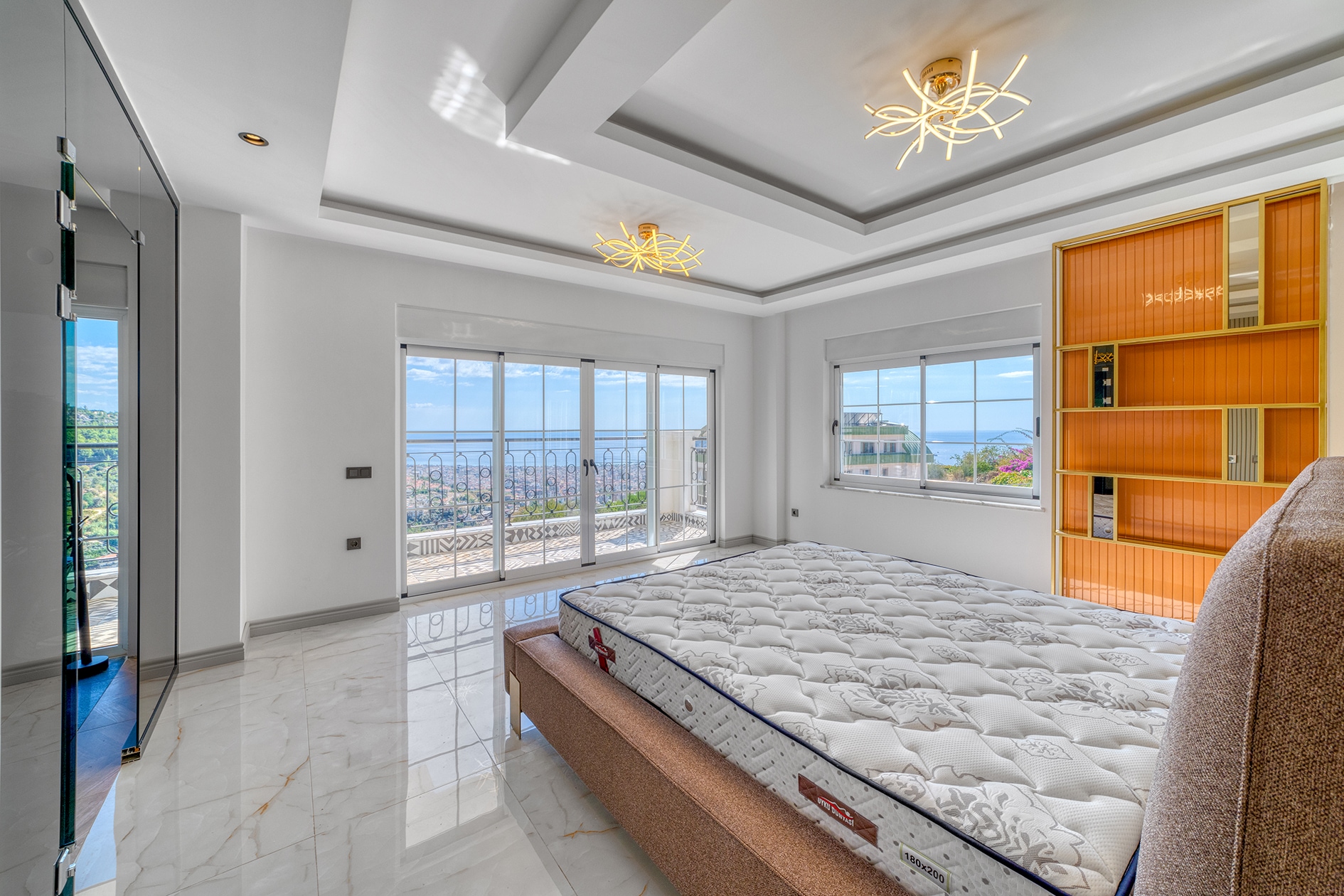 Bed with white mattress beside a panoramic balcony door in a bedroom in Alanya