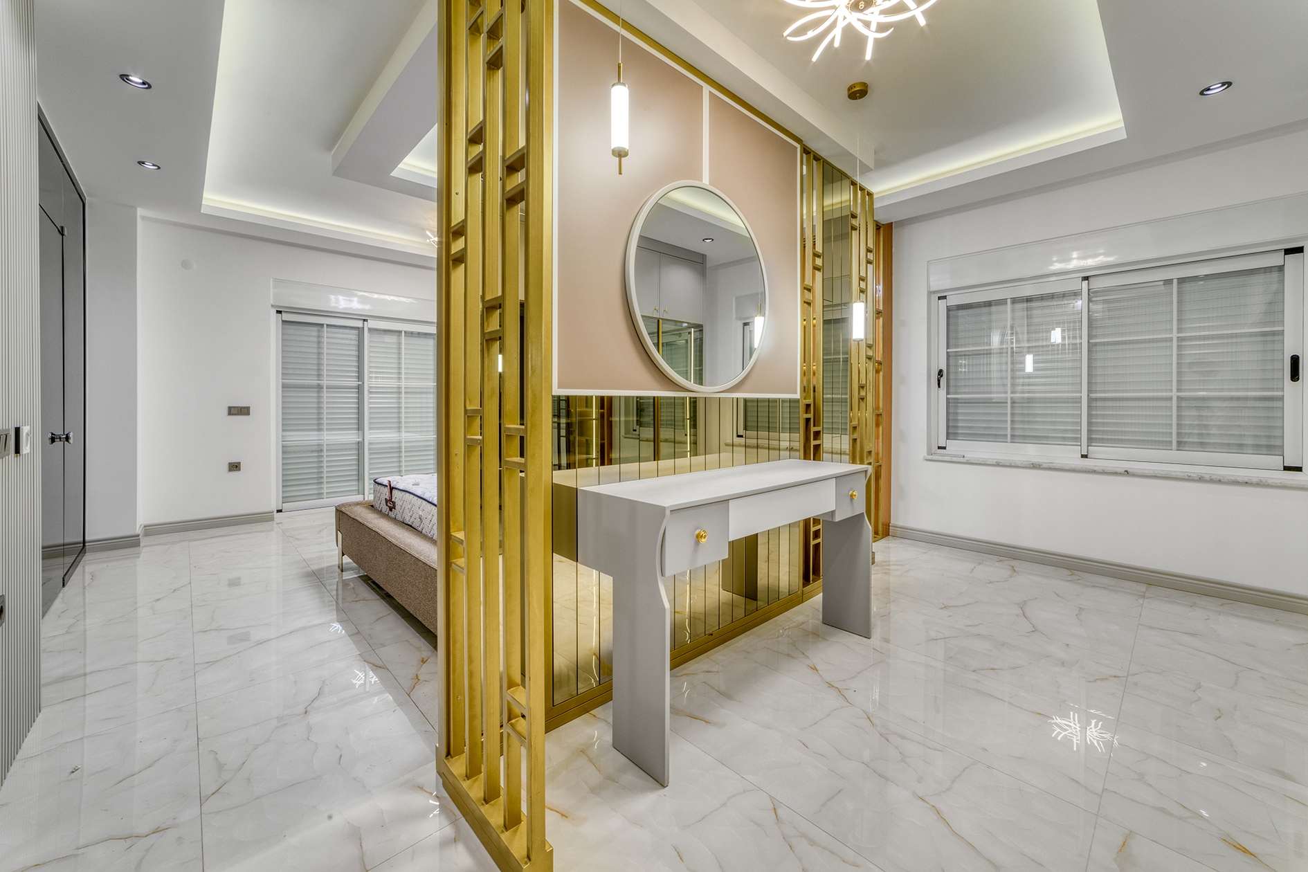 Bed behind a gold glass partition with a white dressing table in a house bedroom in Alanya