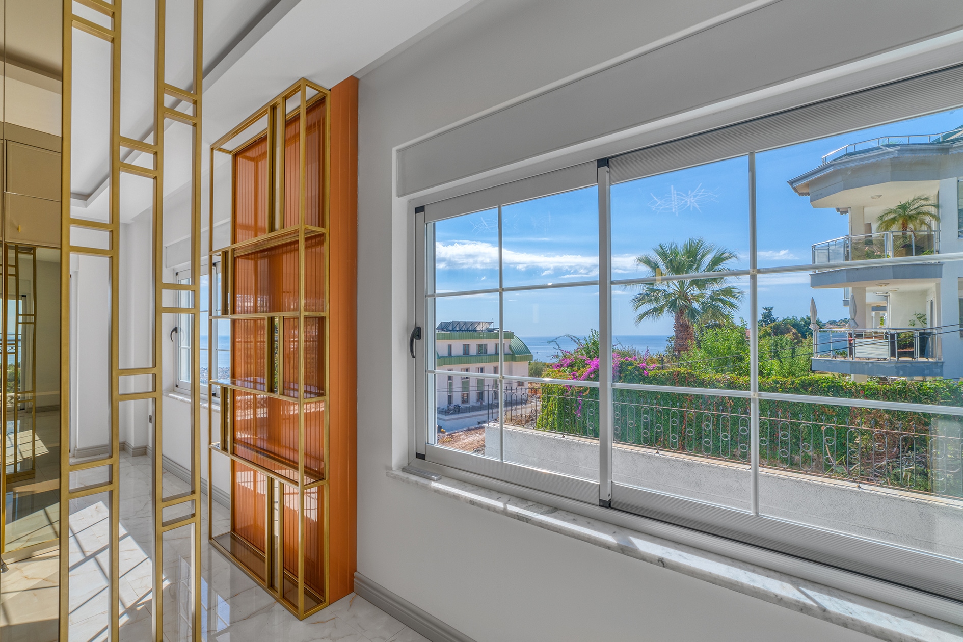 Wide window with orange shelving and a palm outside in a villa bedroom in Alanya
