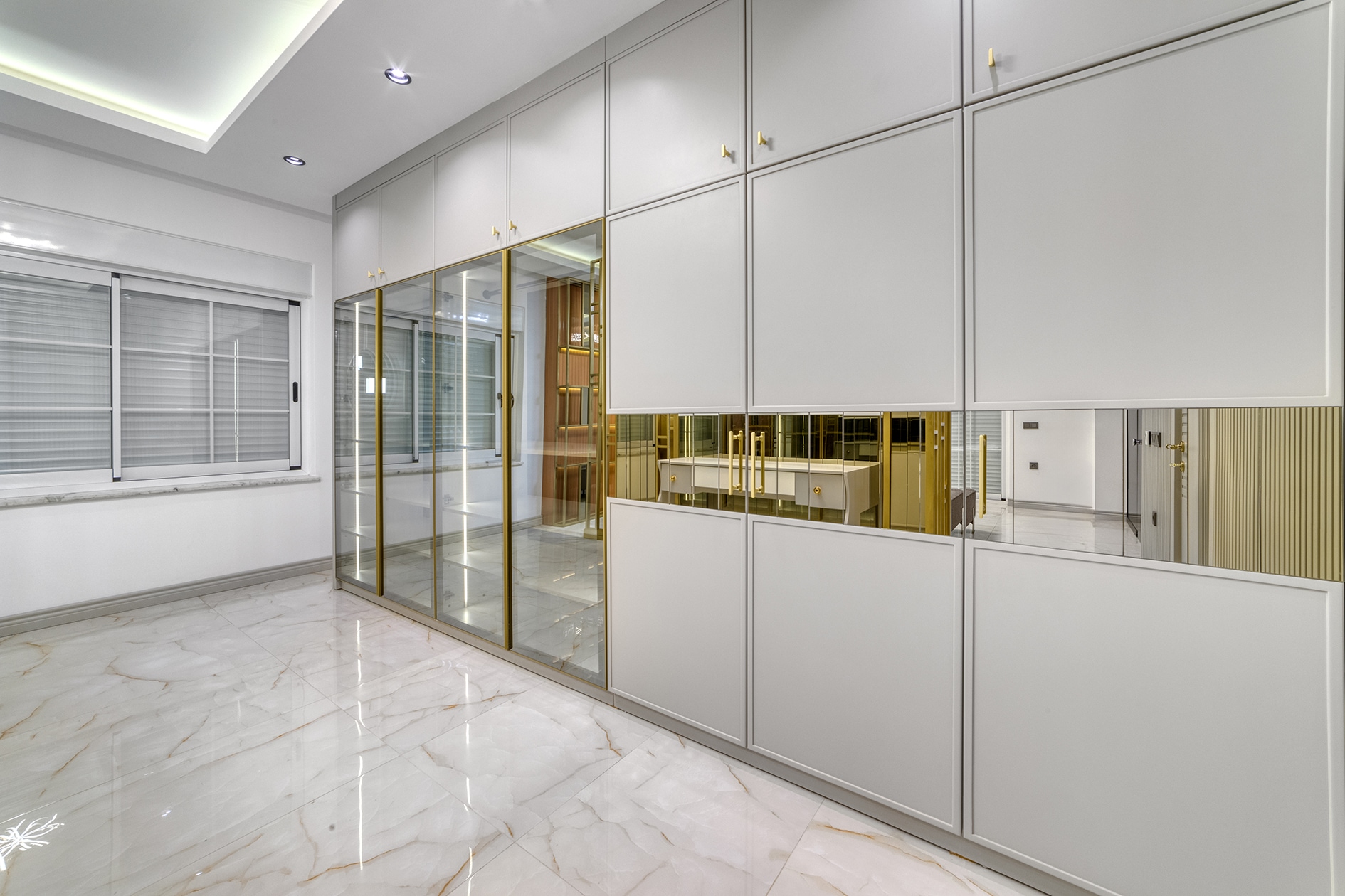 Built-in white cabinetry and a glass partition with gold framing in a villa kitchen