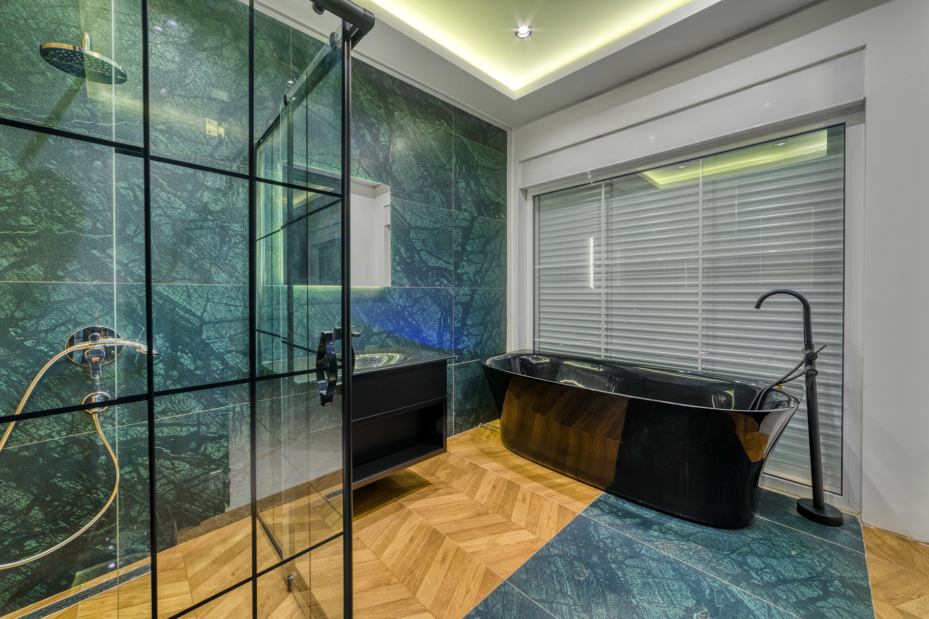 Black freestanding bathtub and framed shower with dark green tile in a house bathroom in Alanya