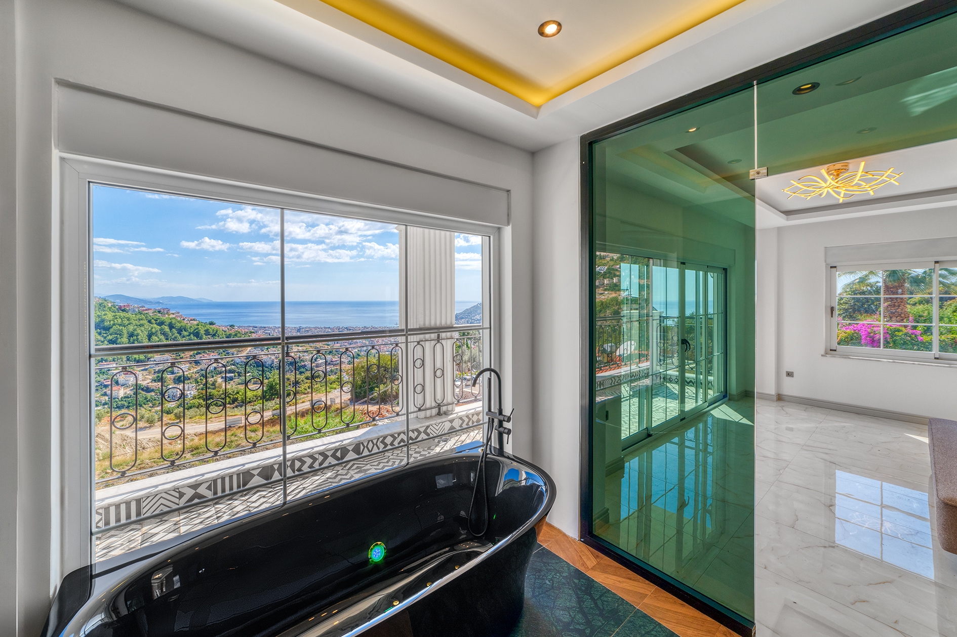 Black freestanding bathtub beside a panoramic window overlooking mountains and sea