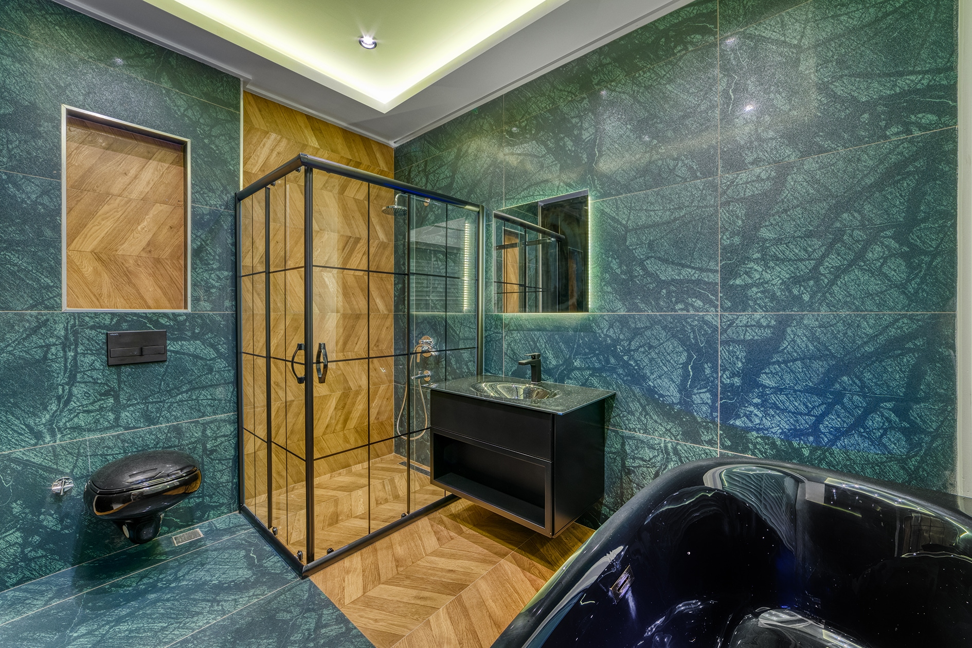 Glass shower enclosure, black bathtub and vanity in a bathroom in Alanya