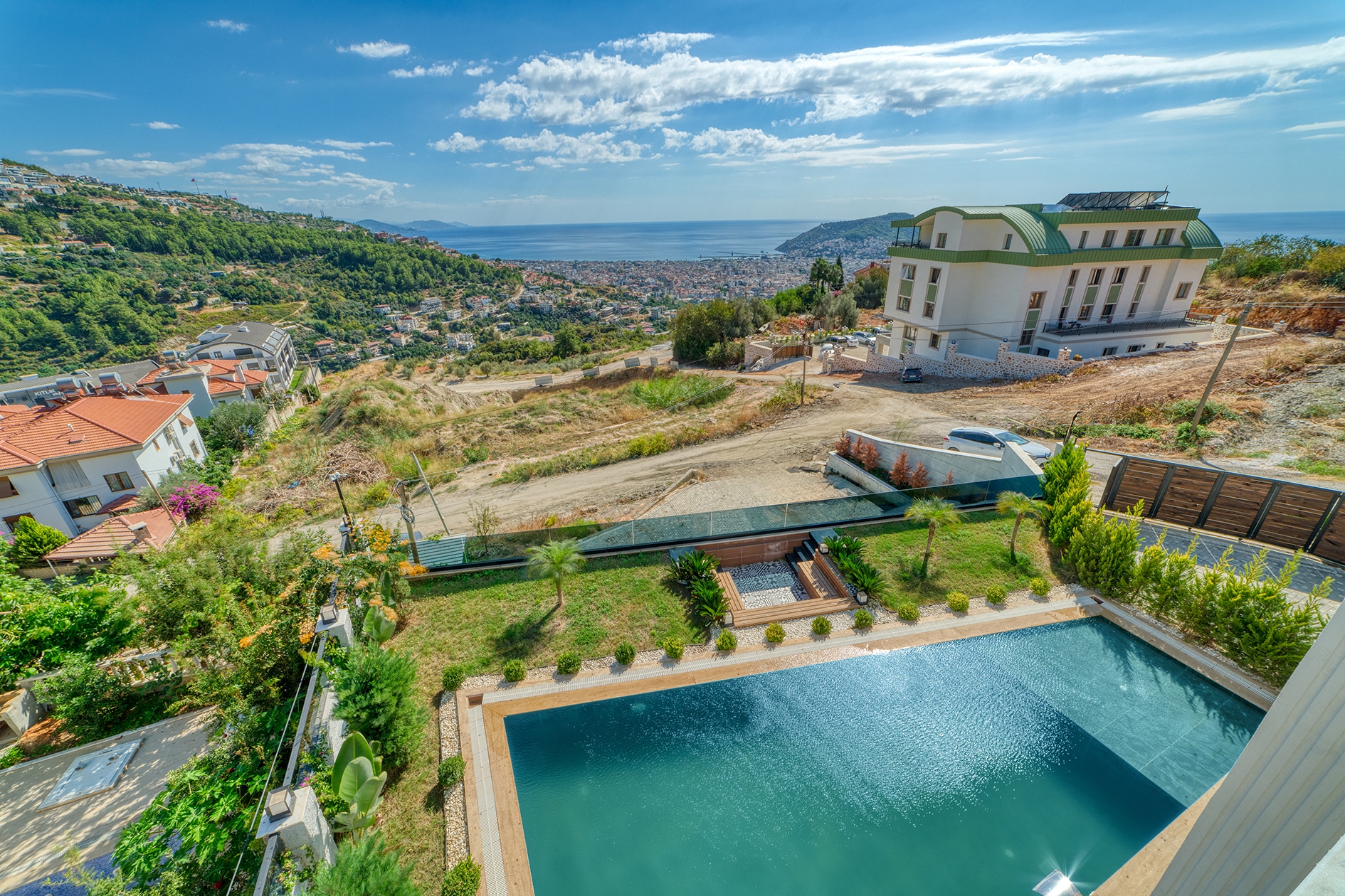 Outdoor pool with wooden decking and sea views beside a 5+1 villa for sale in Turkey