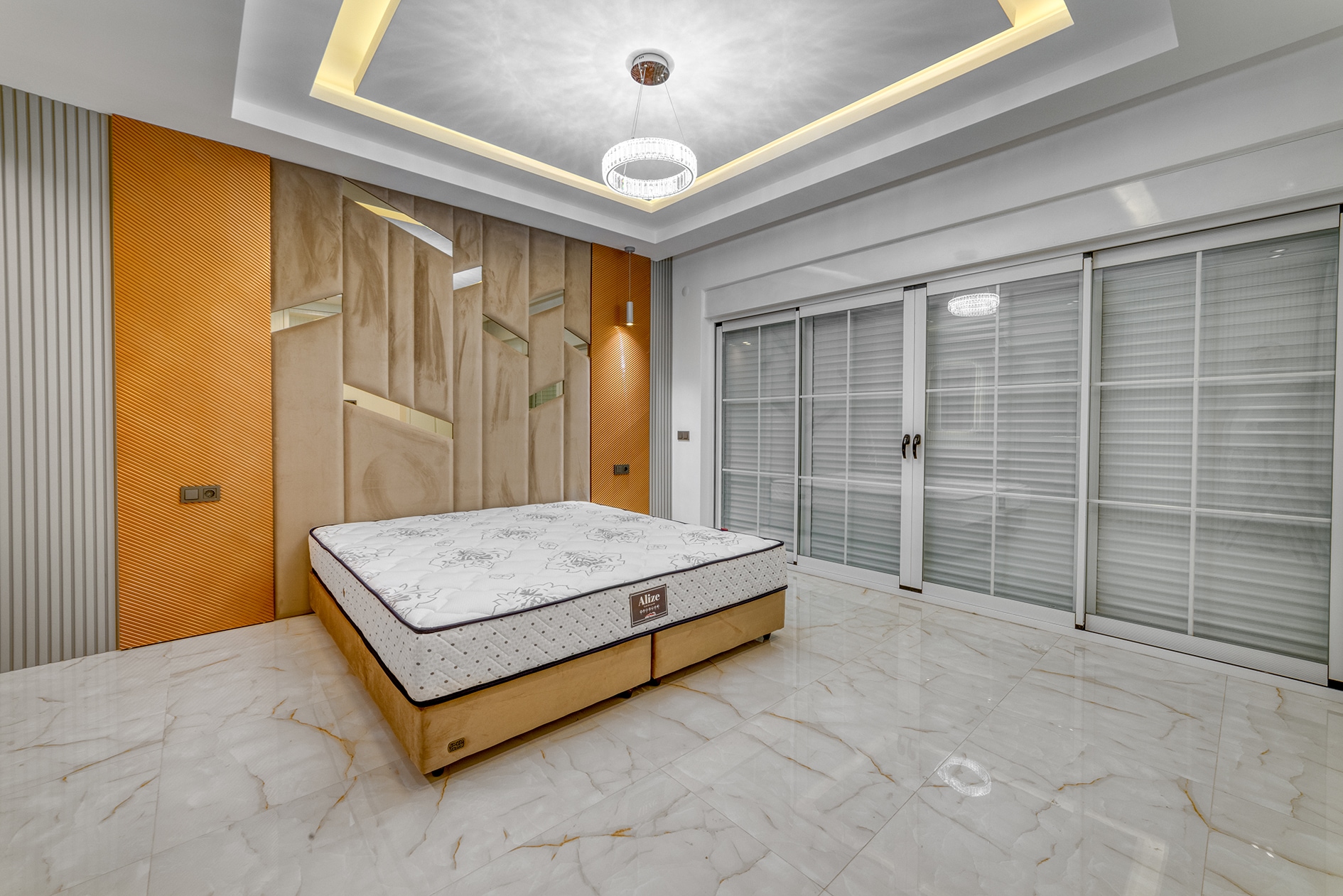 Double bed beside an orange-paneled accent wall in a villa bedroom