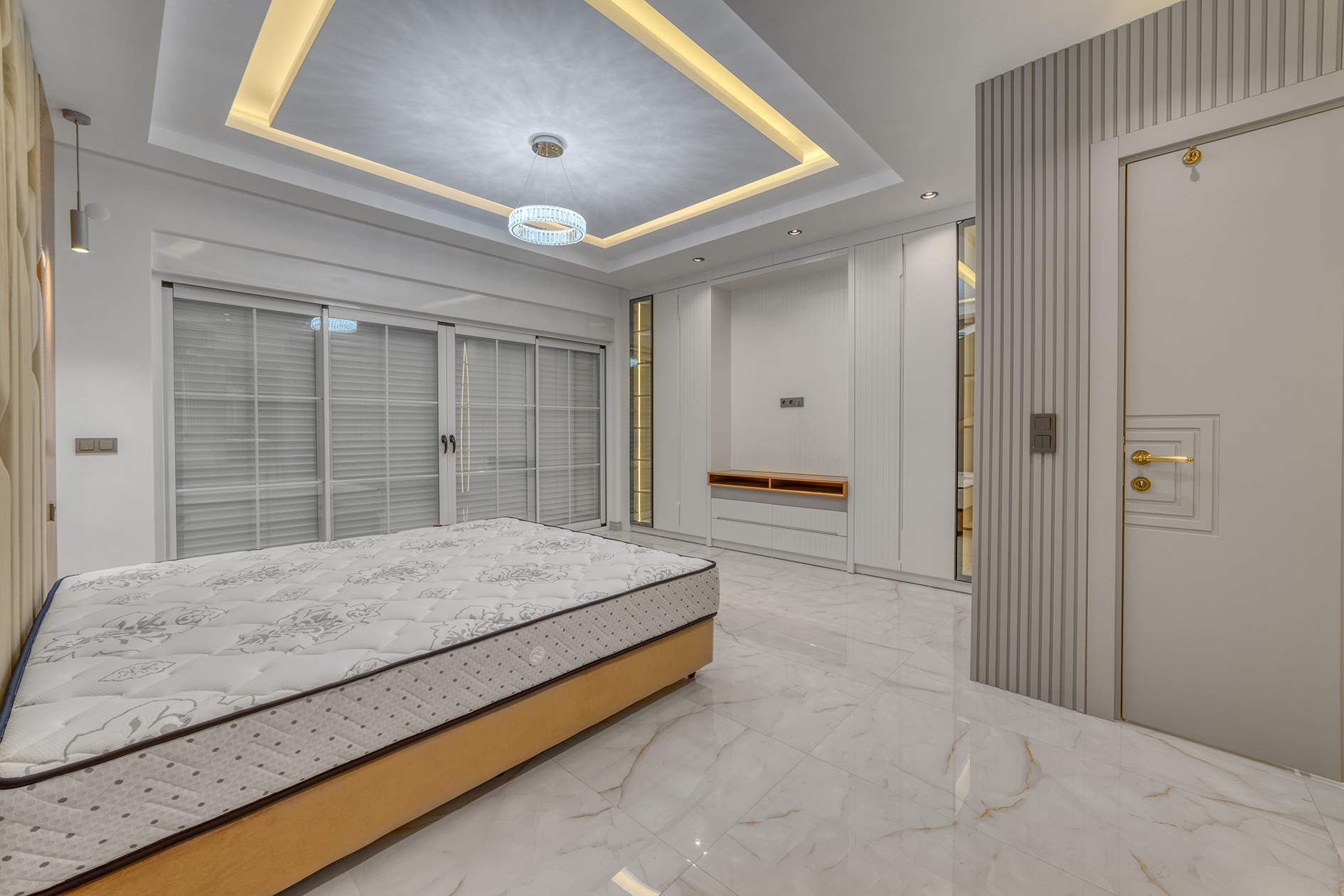Double bed beside panoramic sliding doors and a built-in wall panel
