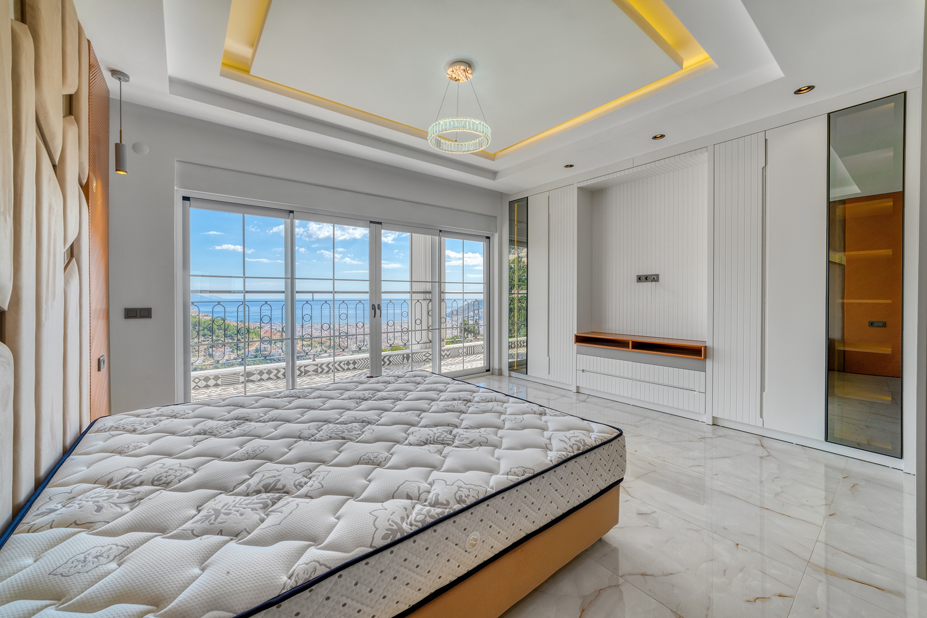 Double bed and white wardrobe beside panoramic balcony doors in a bedroom in Alanya