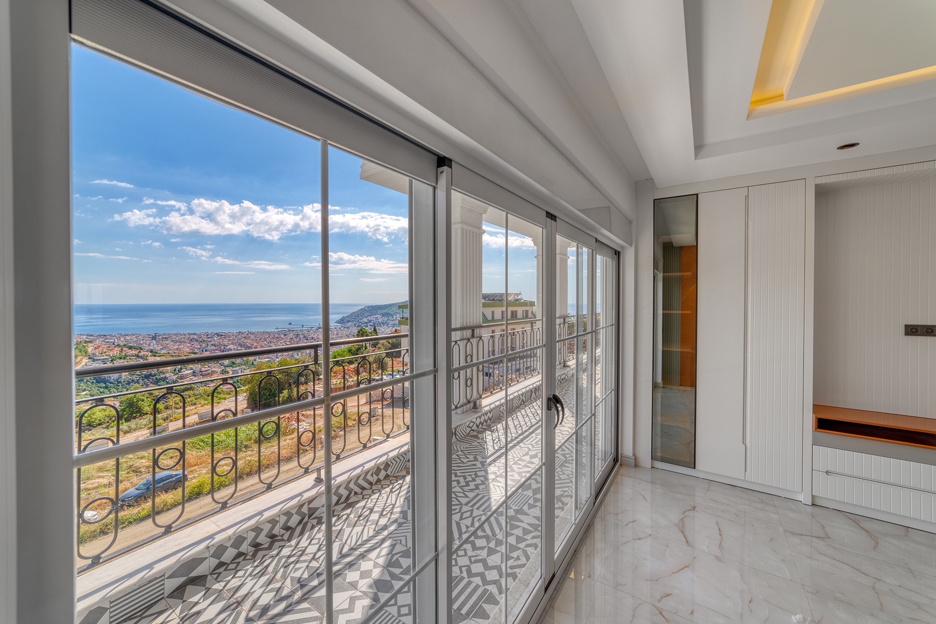Panoramic windows, balcony and views of the city and coast beside a villa