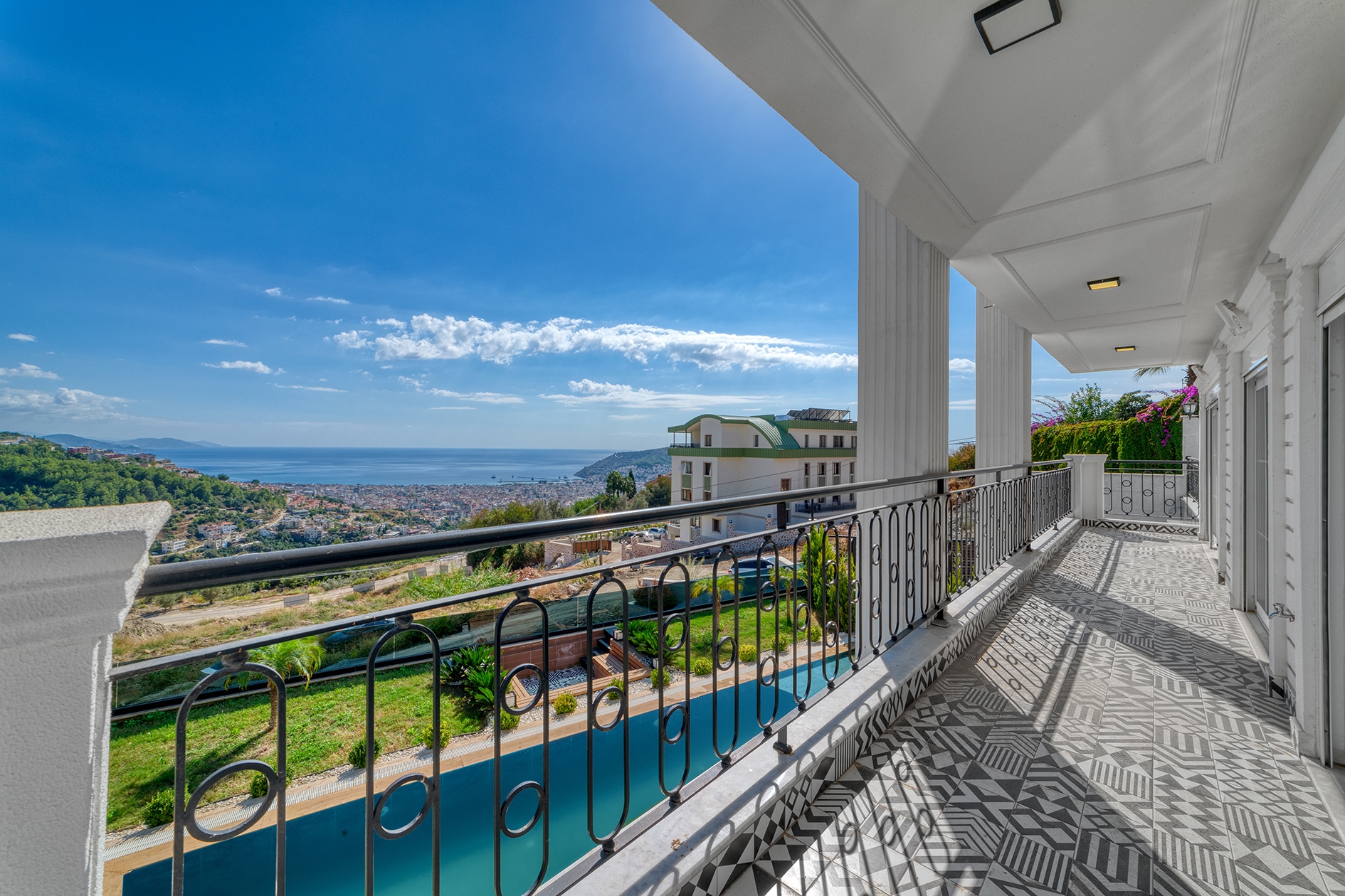Covered terrace with white columns and pool below at a villa for sale in Alanya