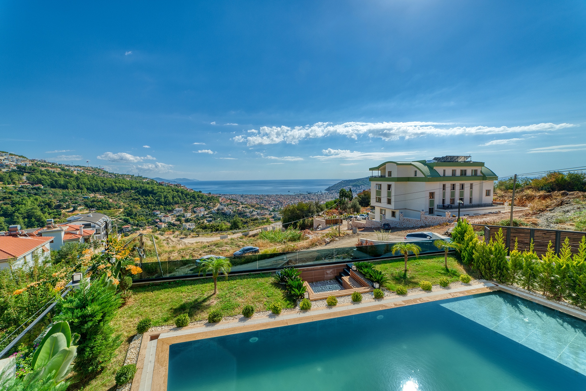 Pool before a landscaped lawn with sea and mountain views beside a villa in Turkey