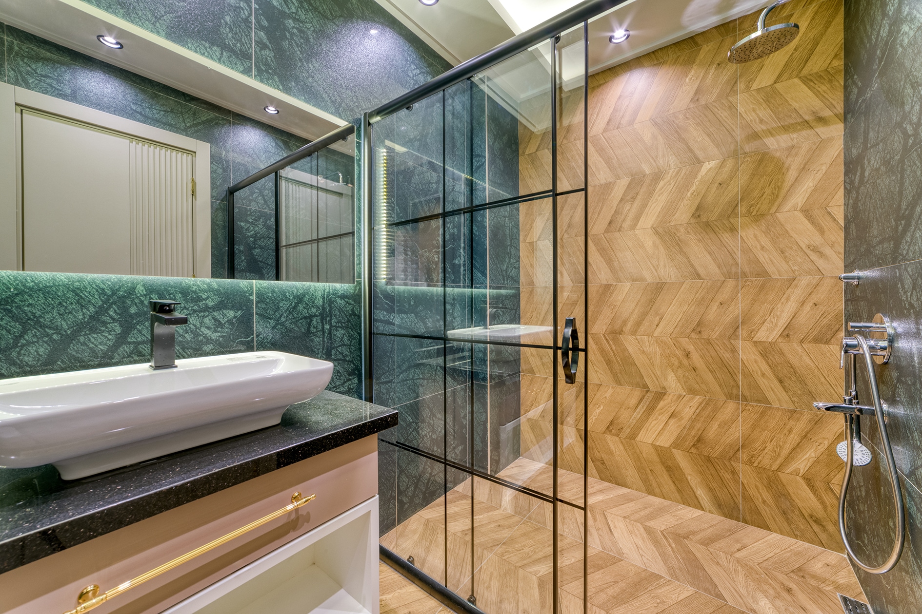 Glass shower enclosure with a black frame and lit mirror in a villa bathroom