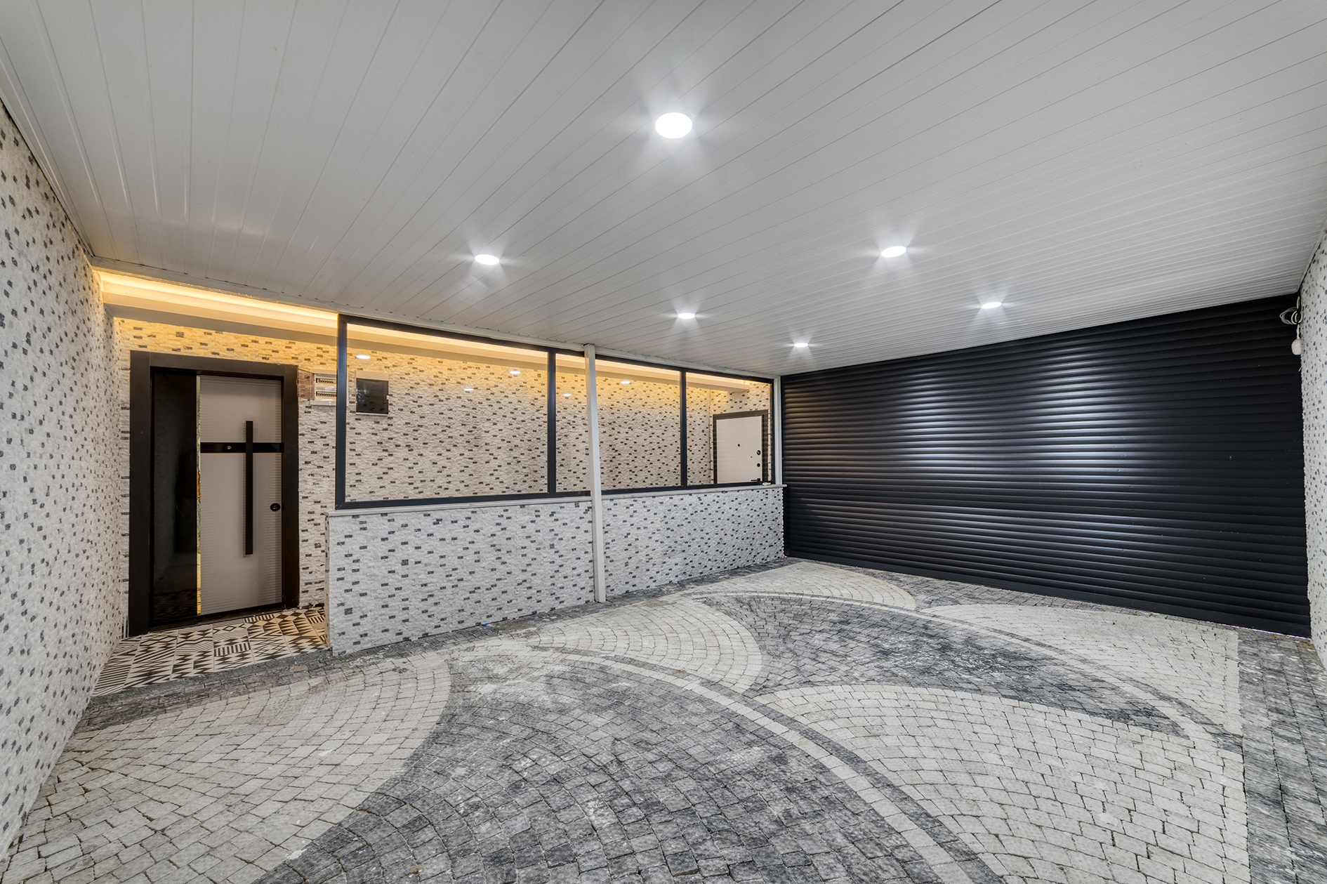 Covered paved area with circular gray-and-white paving and stone-clad walls at a villa for sale in Alanya