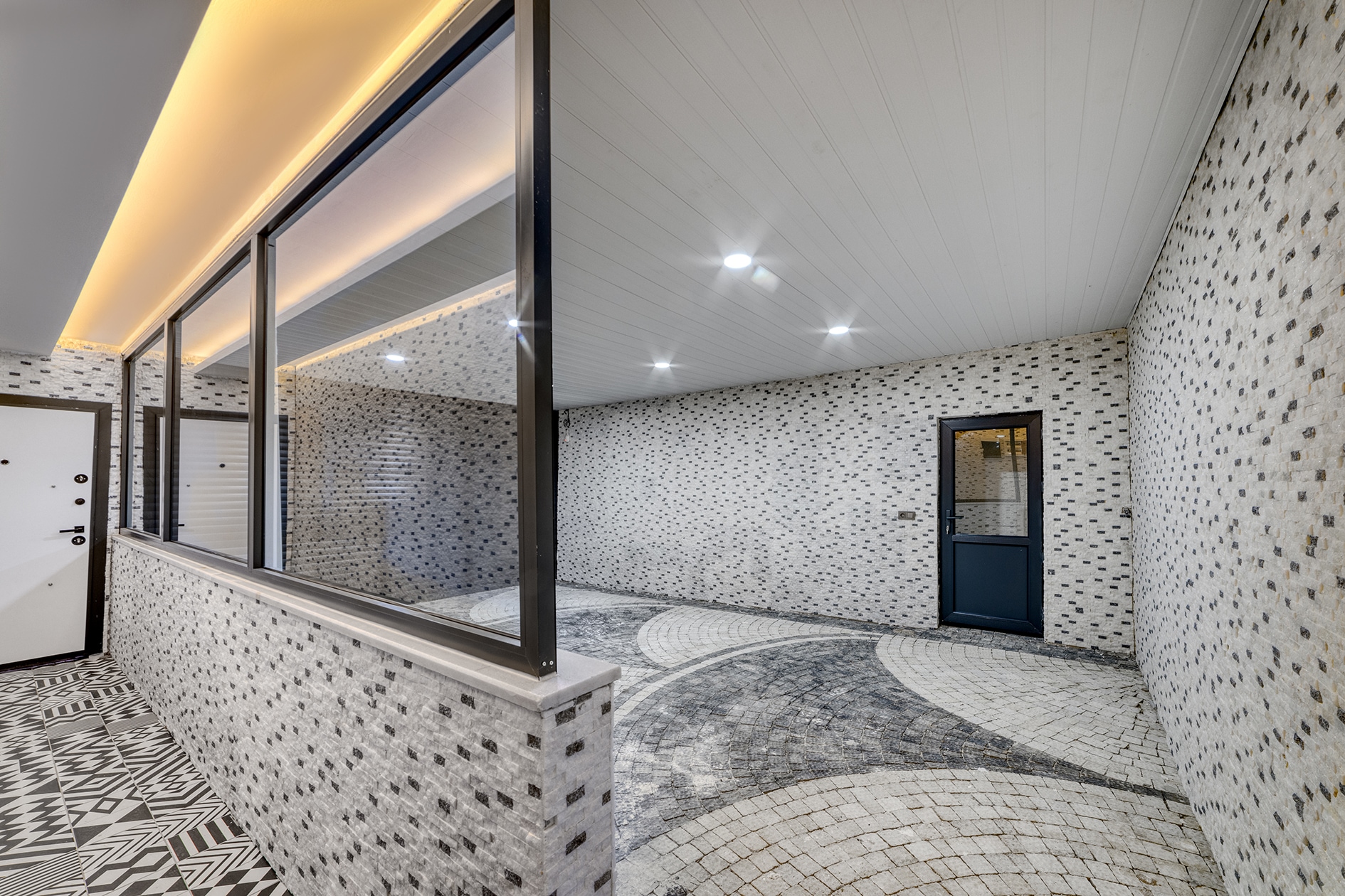 Panoramic glazing beside a covered paved area with a black glazed door and hidden lights in Turkey for sale